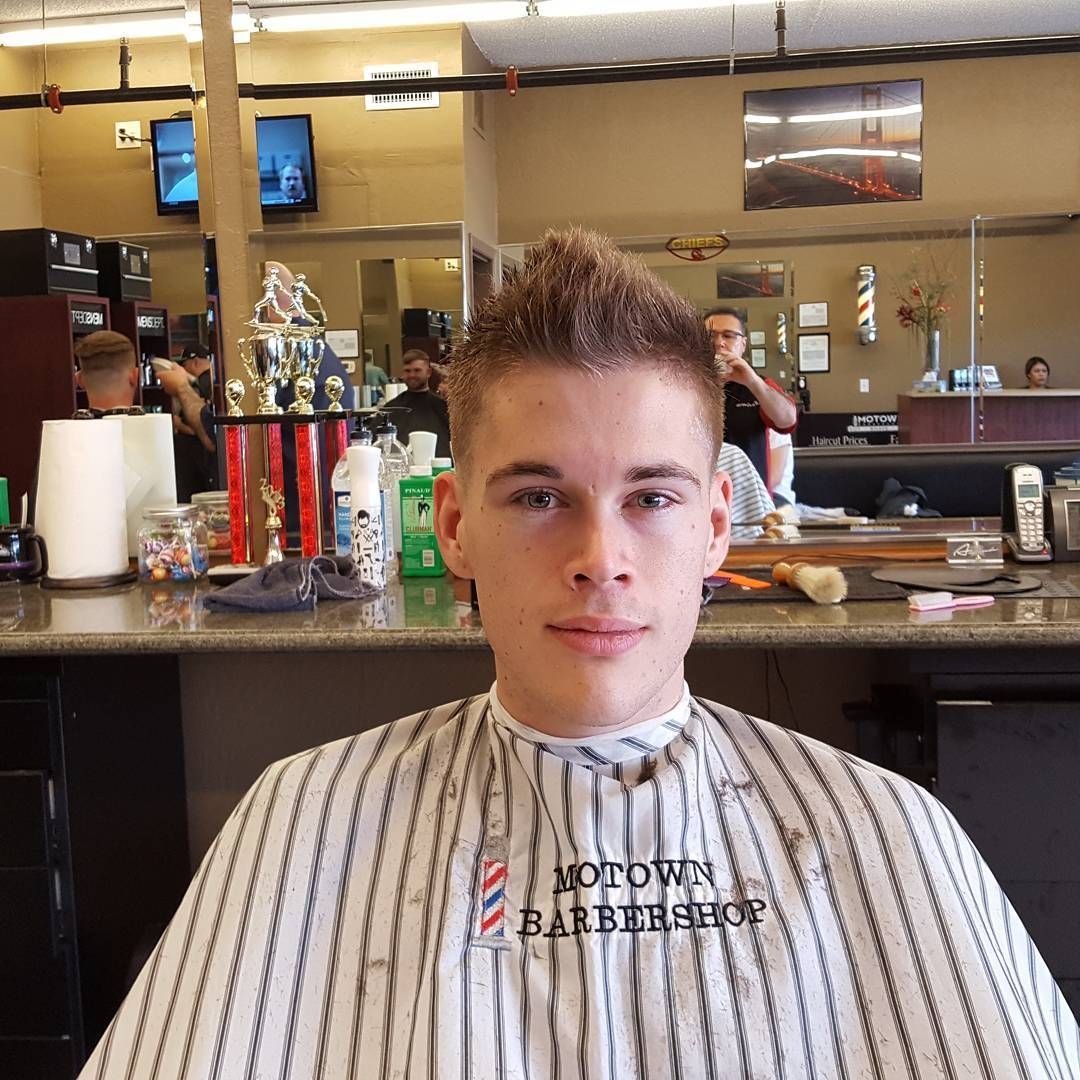 A young man is getting his hair cut at a barber shop