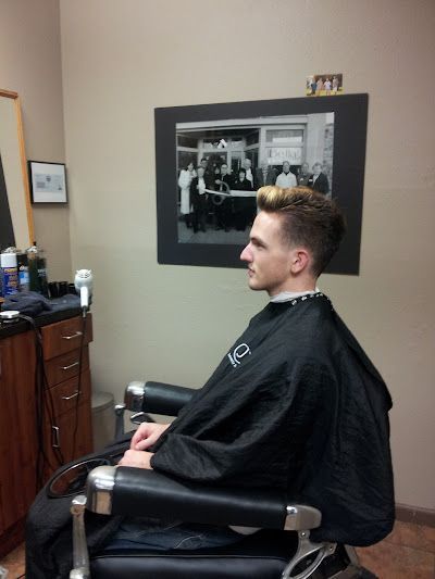 A man in a black cape is sitting in a barber chair