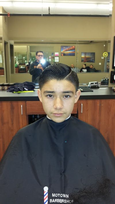 A young boy is getting his hair cut at a barber shop.