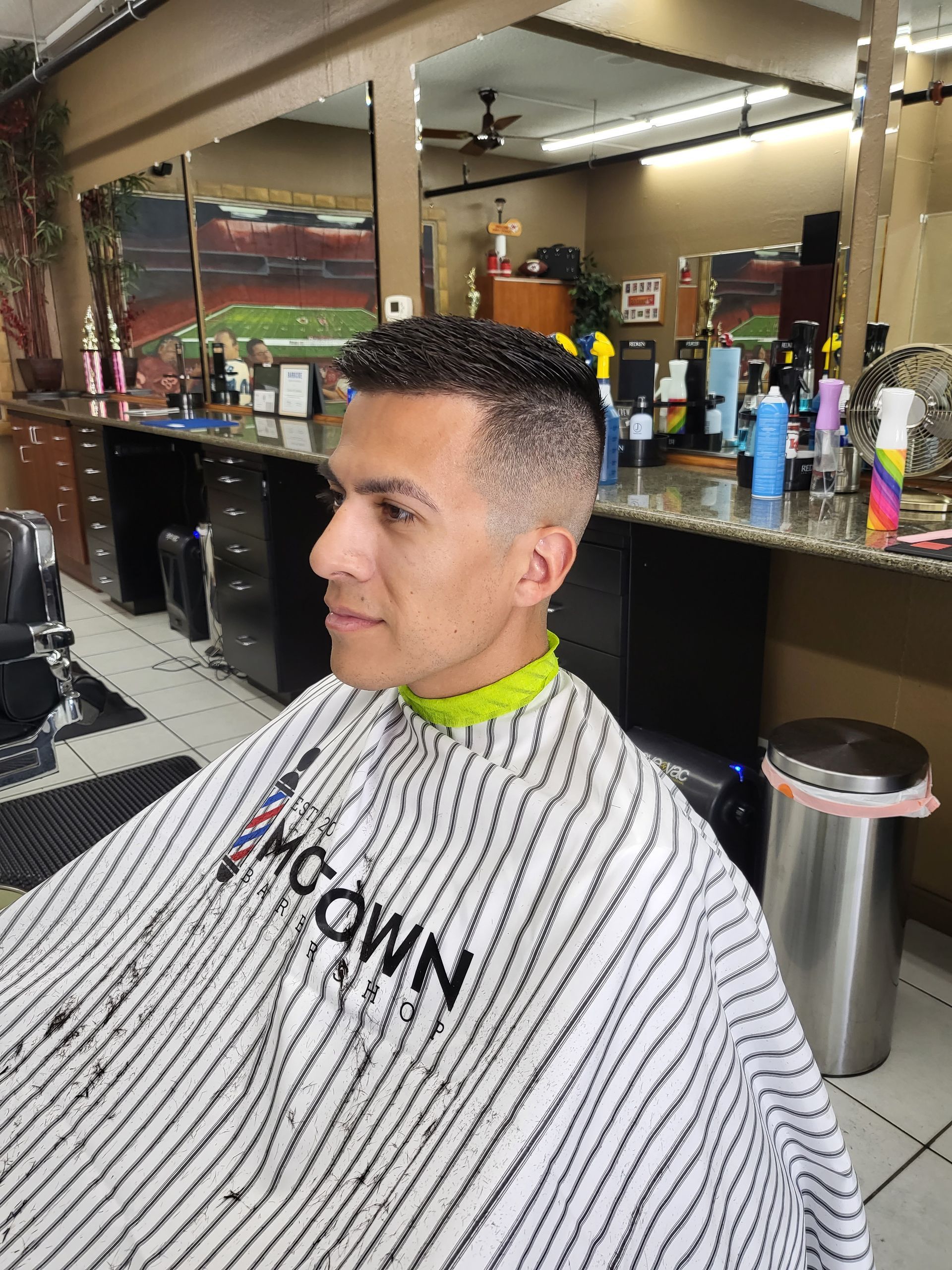 A man is getting his hair cut at a barber shop.