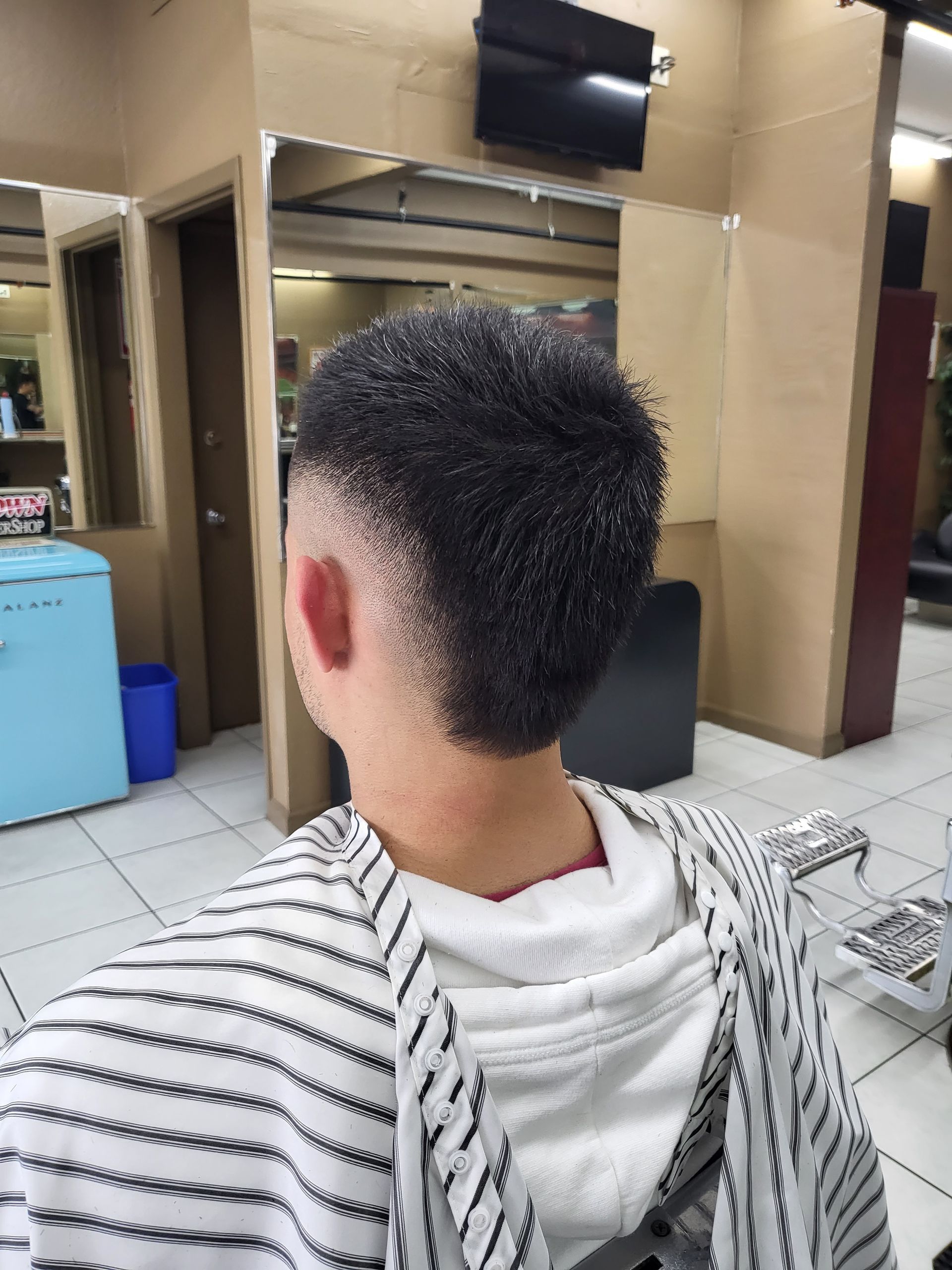 A man is getting his hair cut at a barber shop.