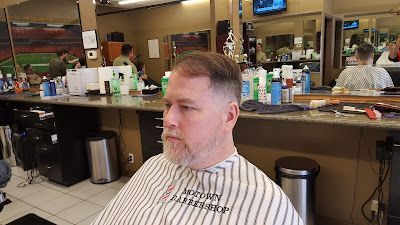 A man is getting his hair cut at a barber shop.