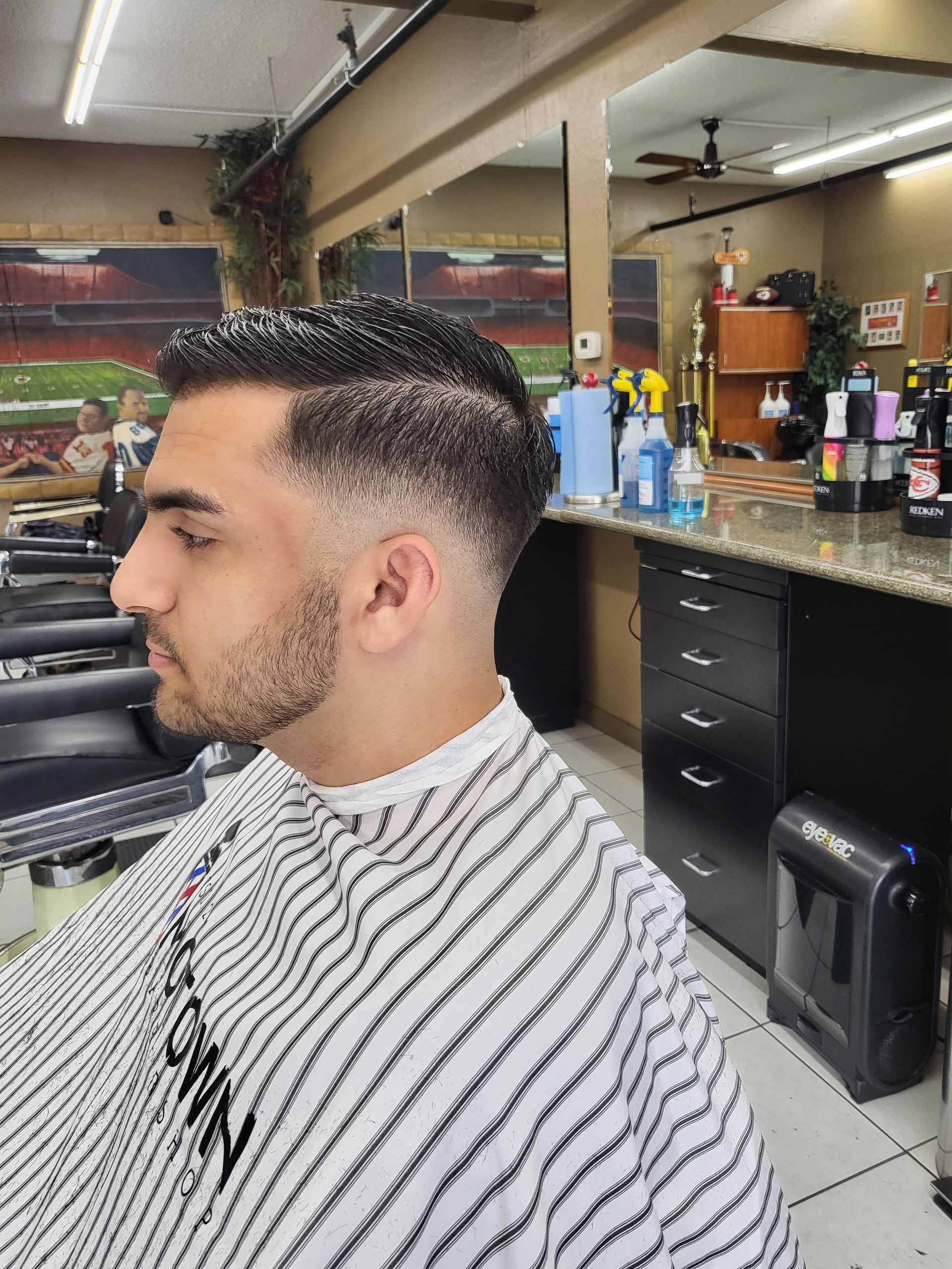 A man is getting his hair cut at a barber shop.