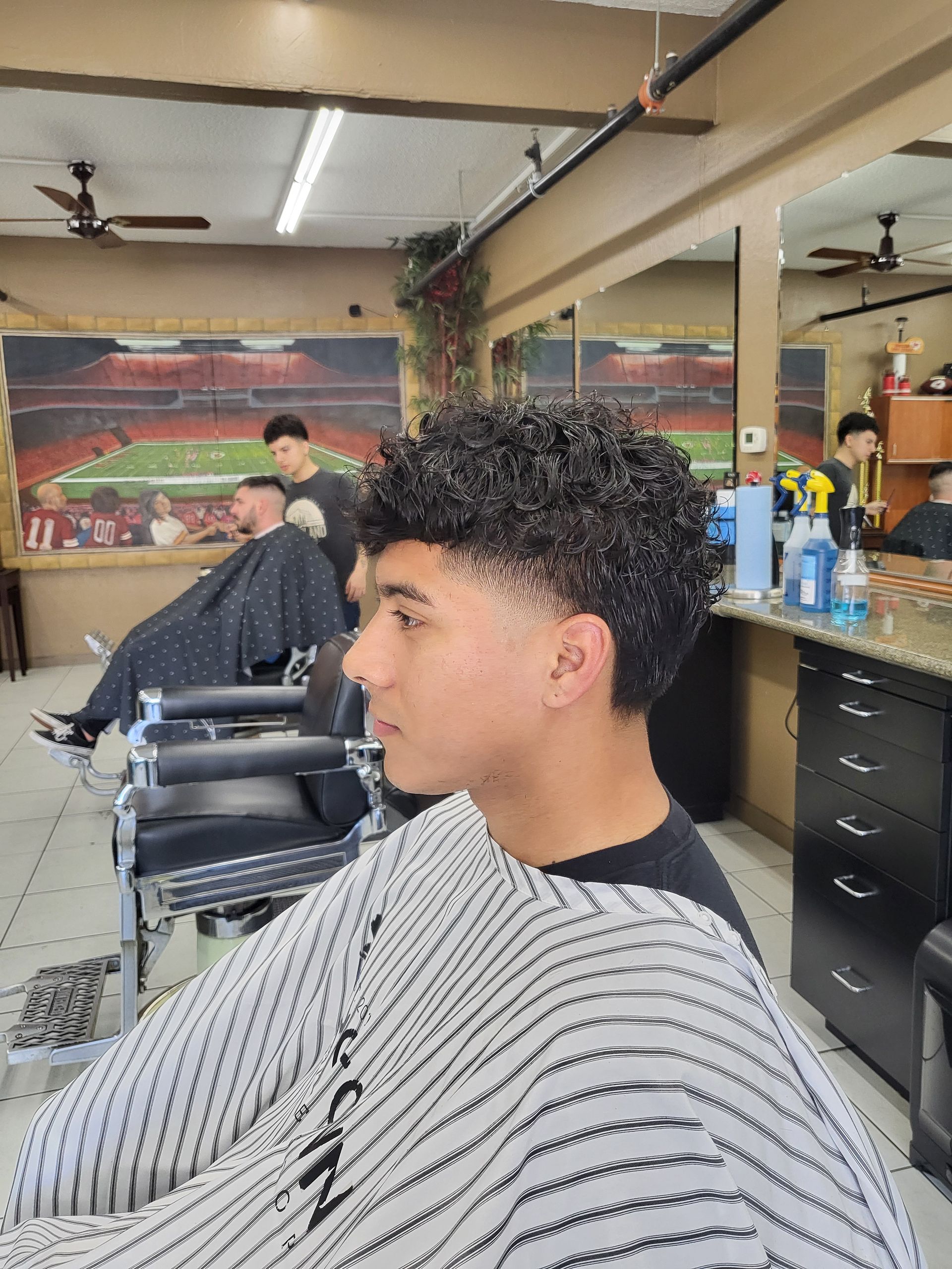 A young man is getting his hair cut at a barber shop.