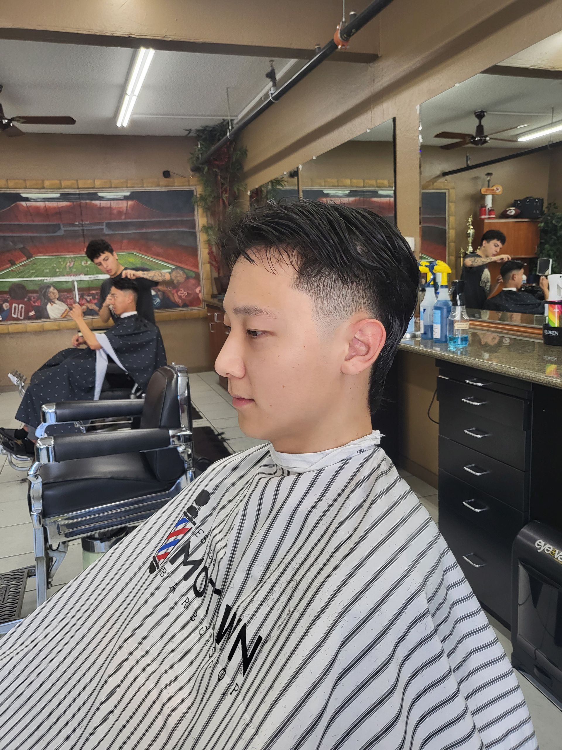 A man is getting his hair cut at a barber shop.