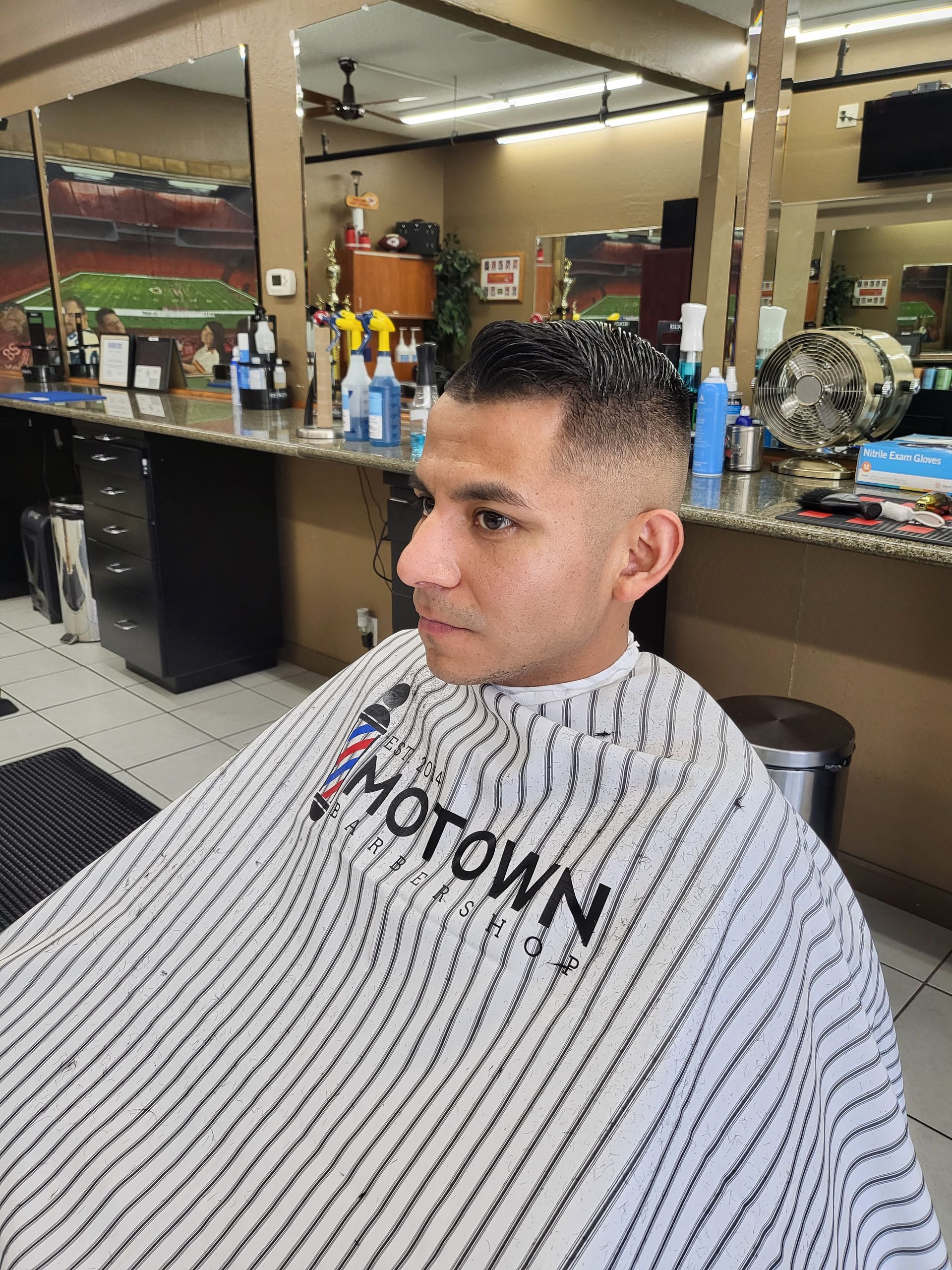A man is getting his hair cut at a barber shop.