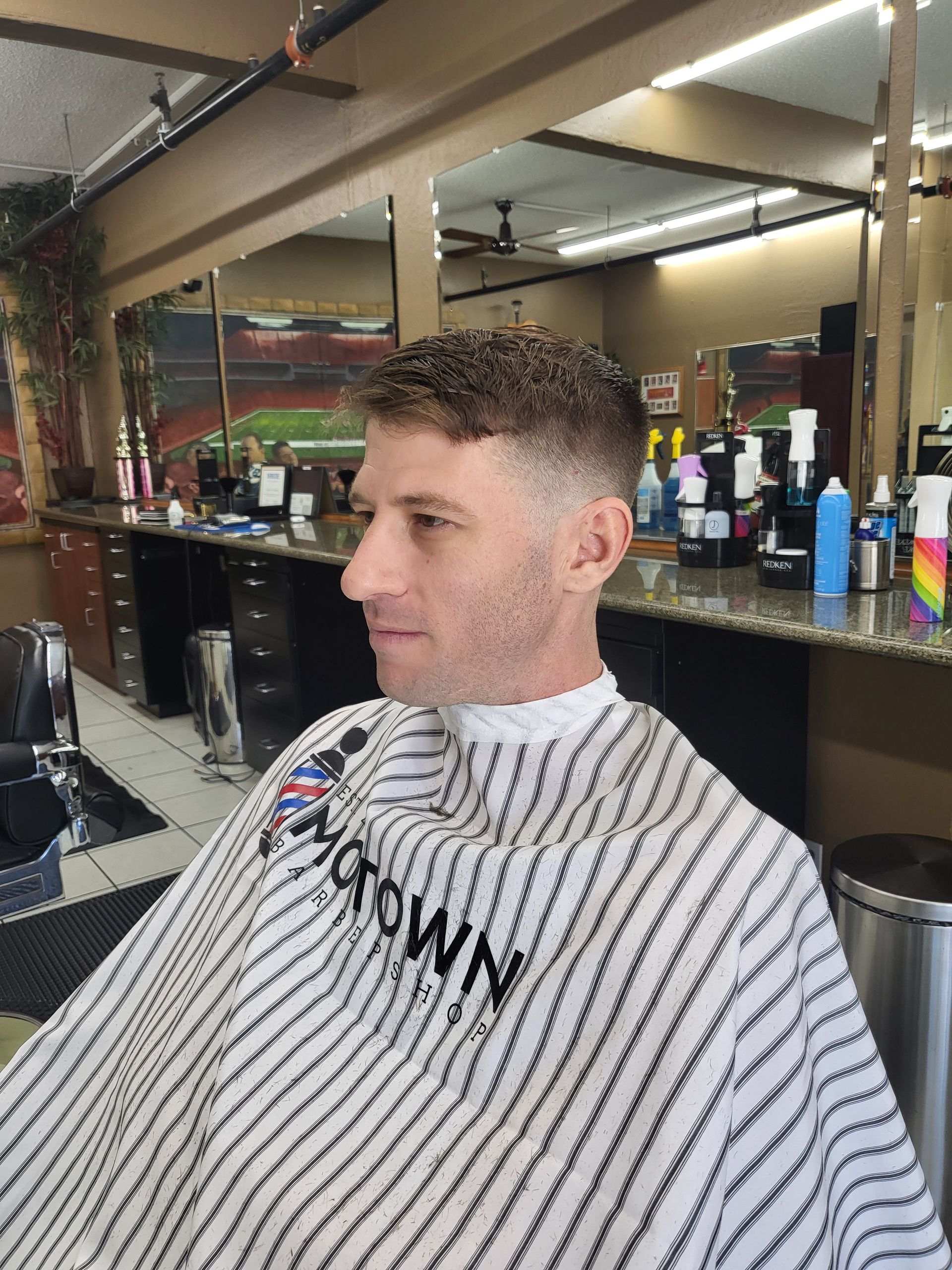 A man is getting his hair cut at a barber shop.