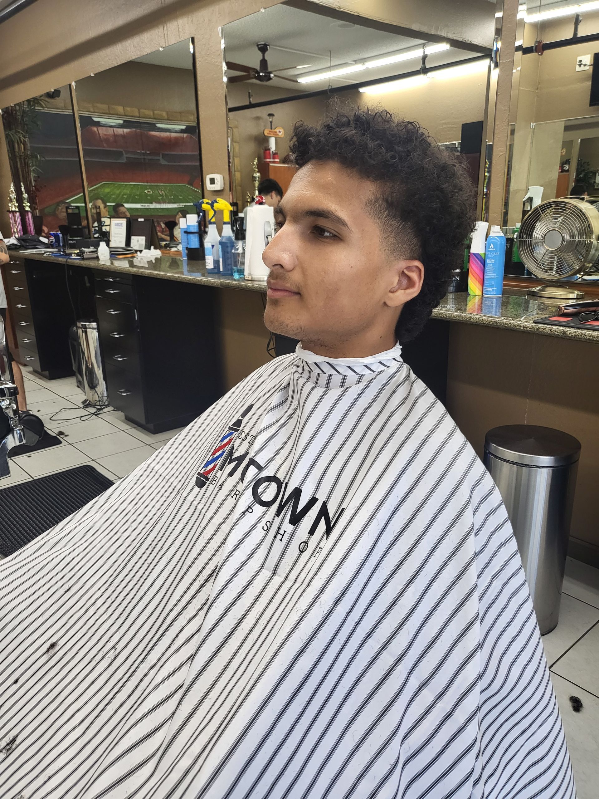 A young man is getting his hair cut at a barber shop.