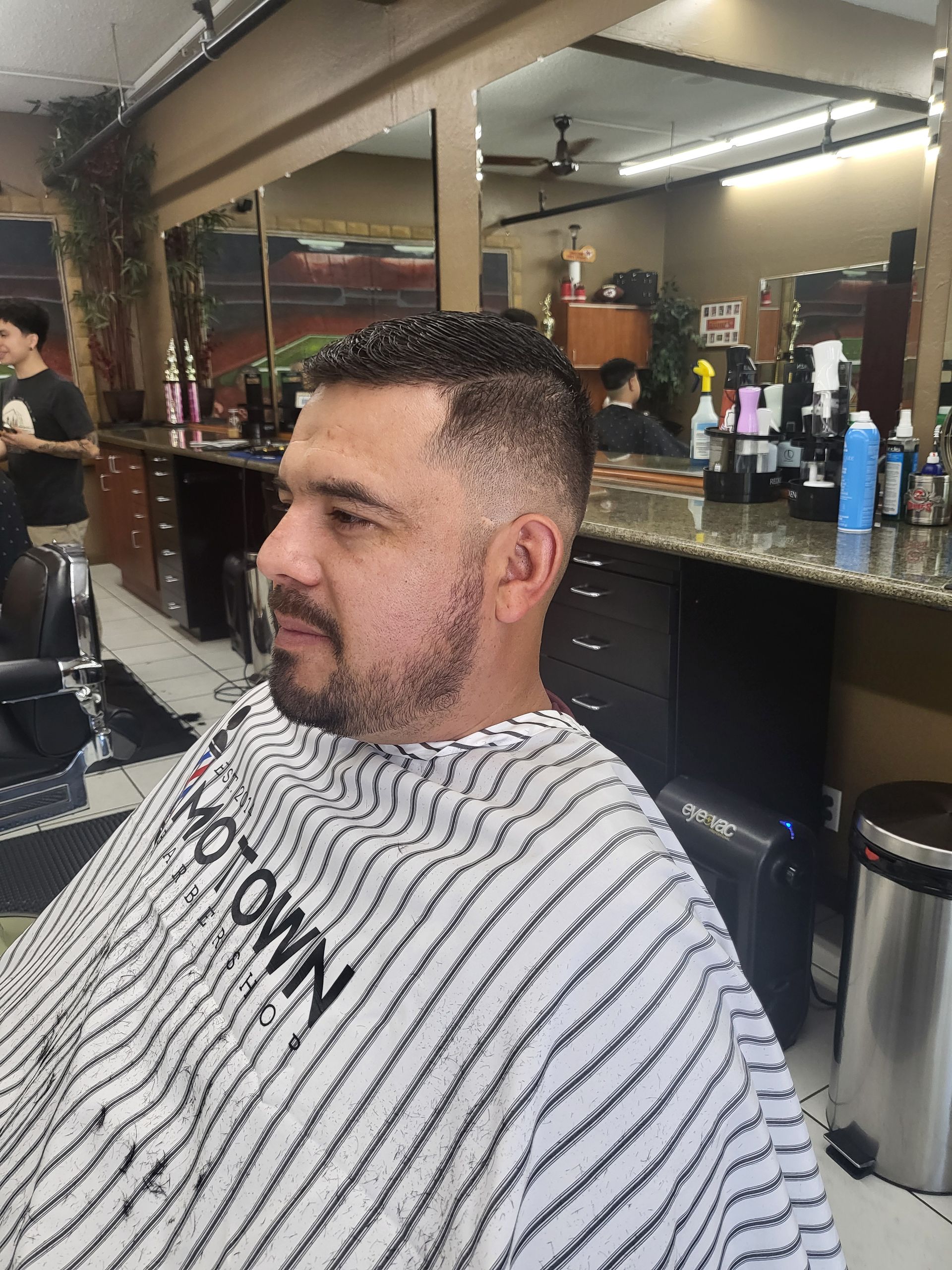 A man is getting his hair cut at a barber shop.