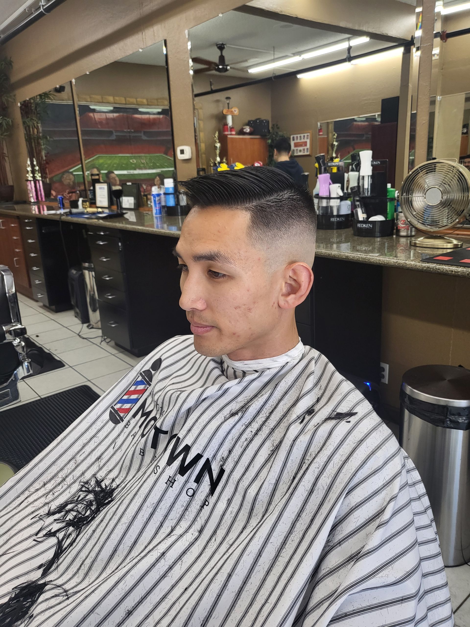 A man is getting his hair cut at a barber shop.
