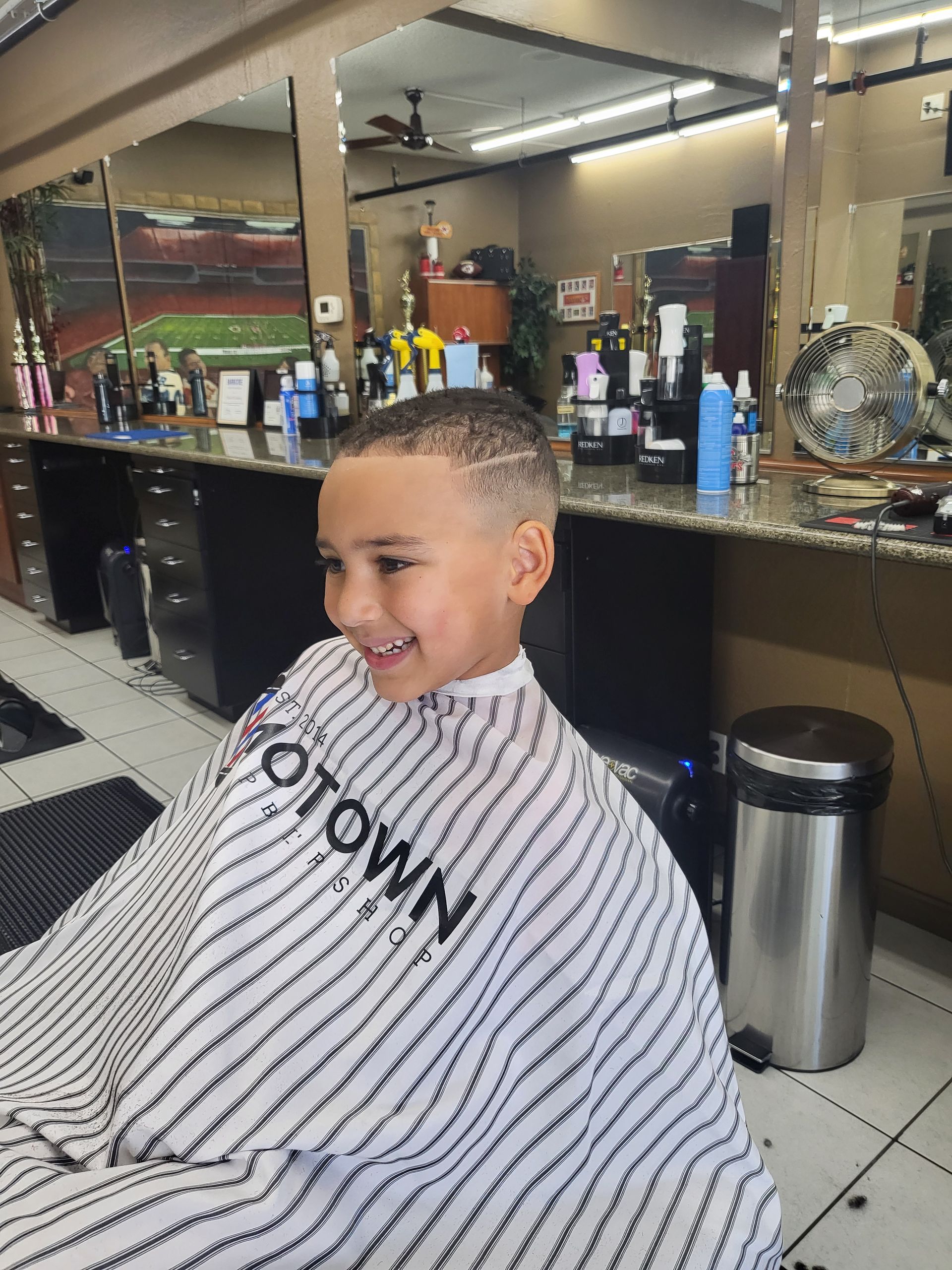 A young boy is getting his hair cut at a barber shop.