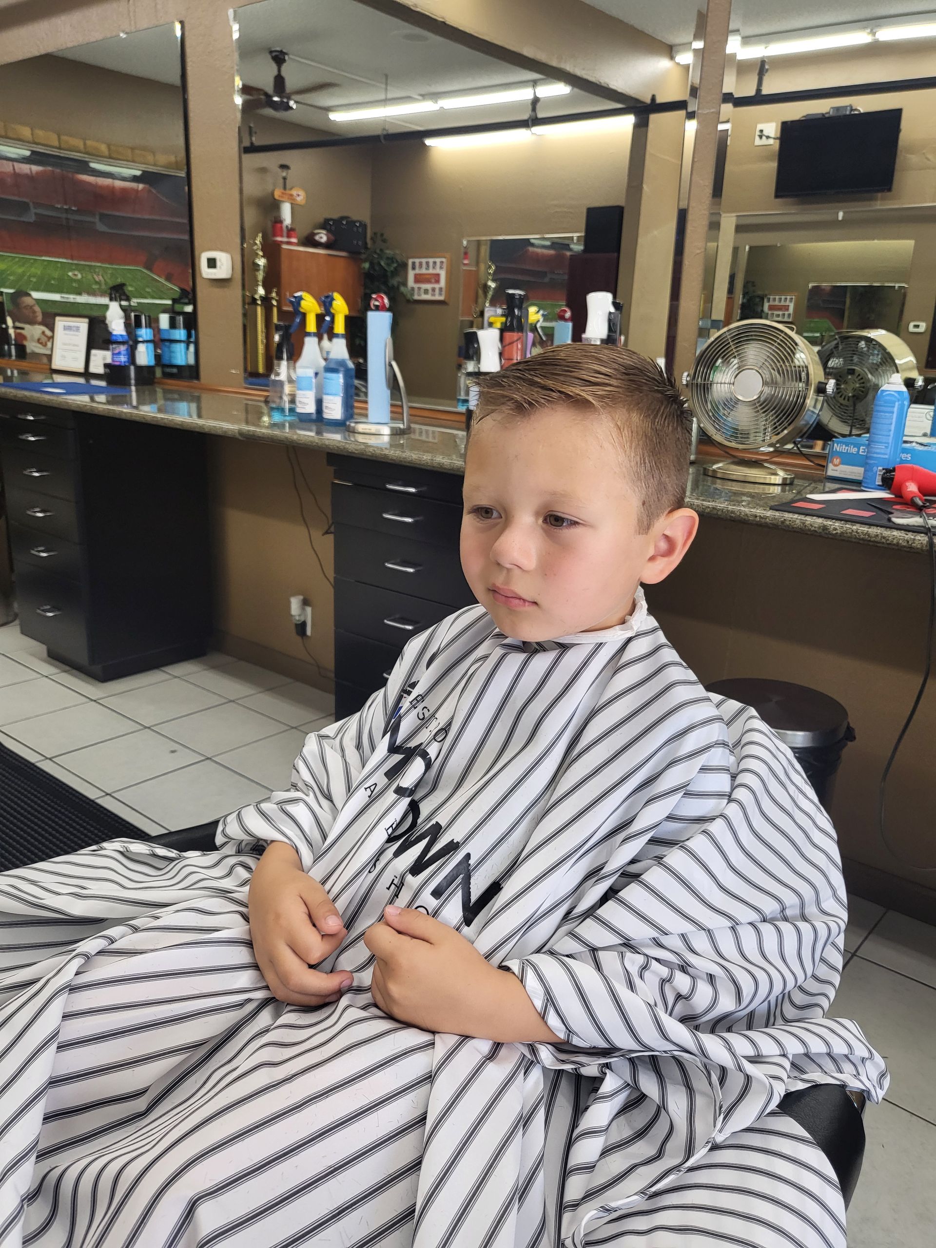 A young boy is getting his hair cut at a barber shop