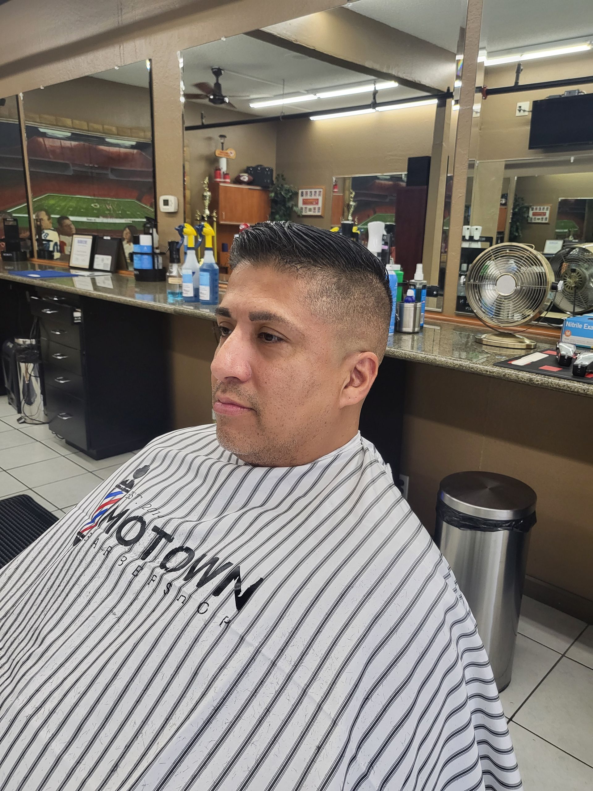 A man is getting his hair cut at a barber shop.