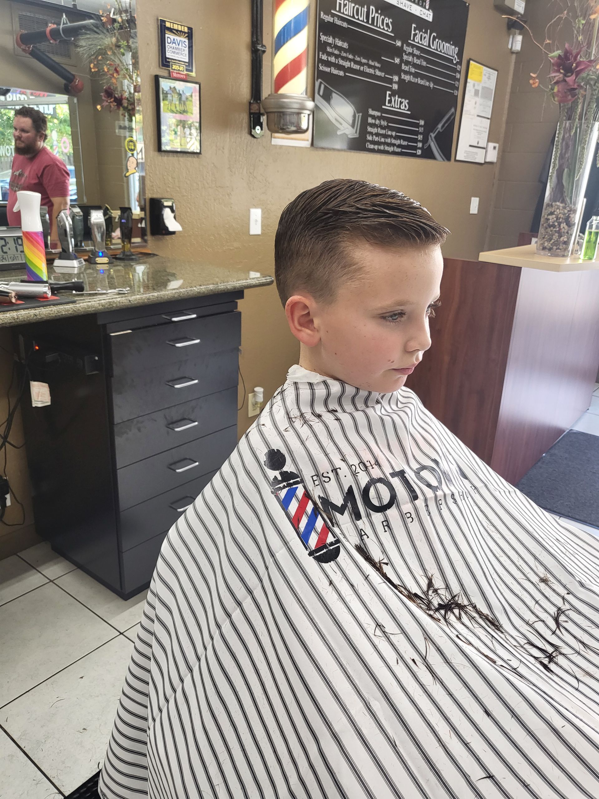 A young boy is getting his hair cut at a barber shop.