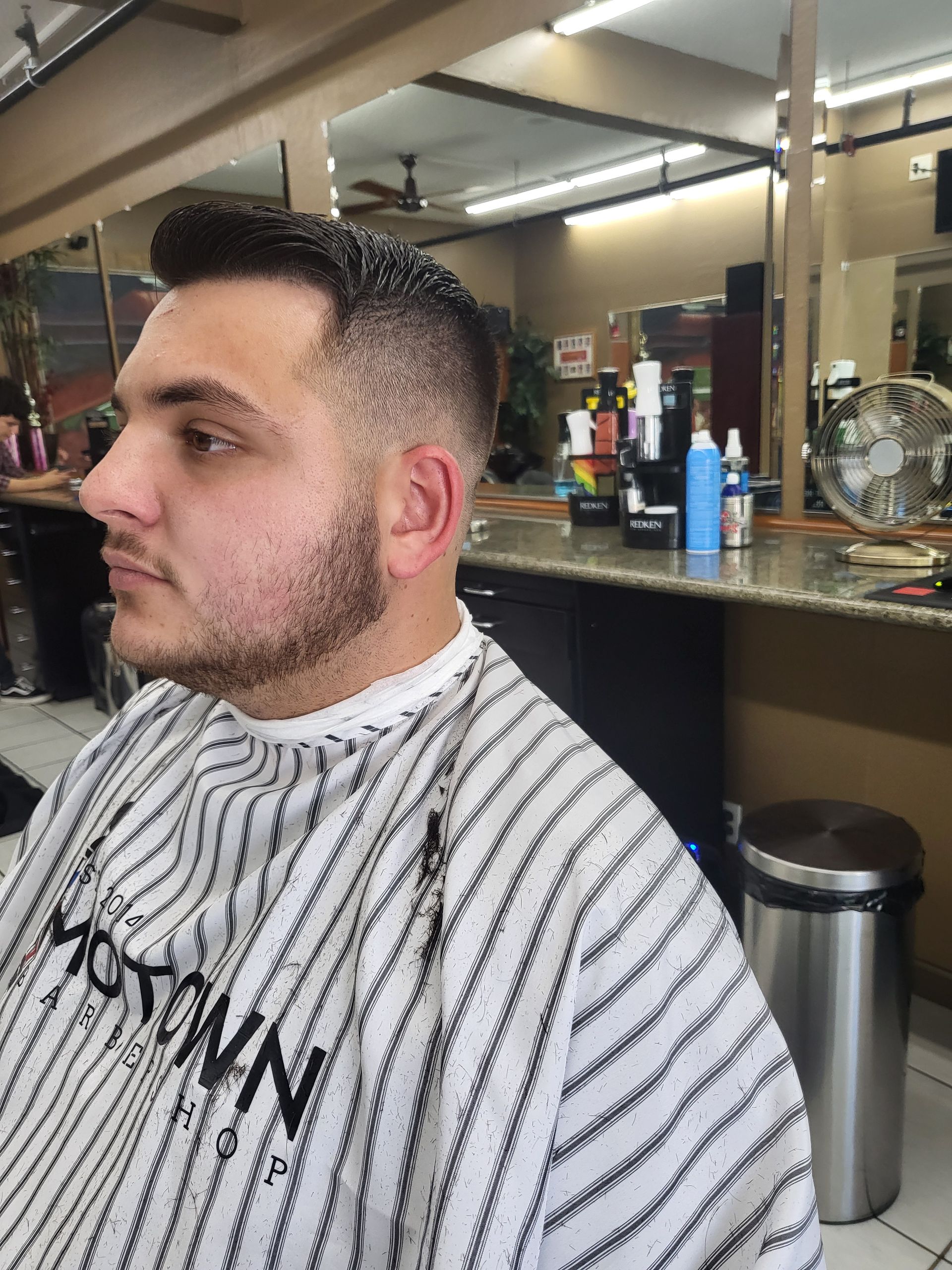 A man is getting his hair cut at a barber shop.