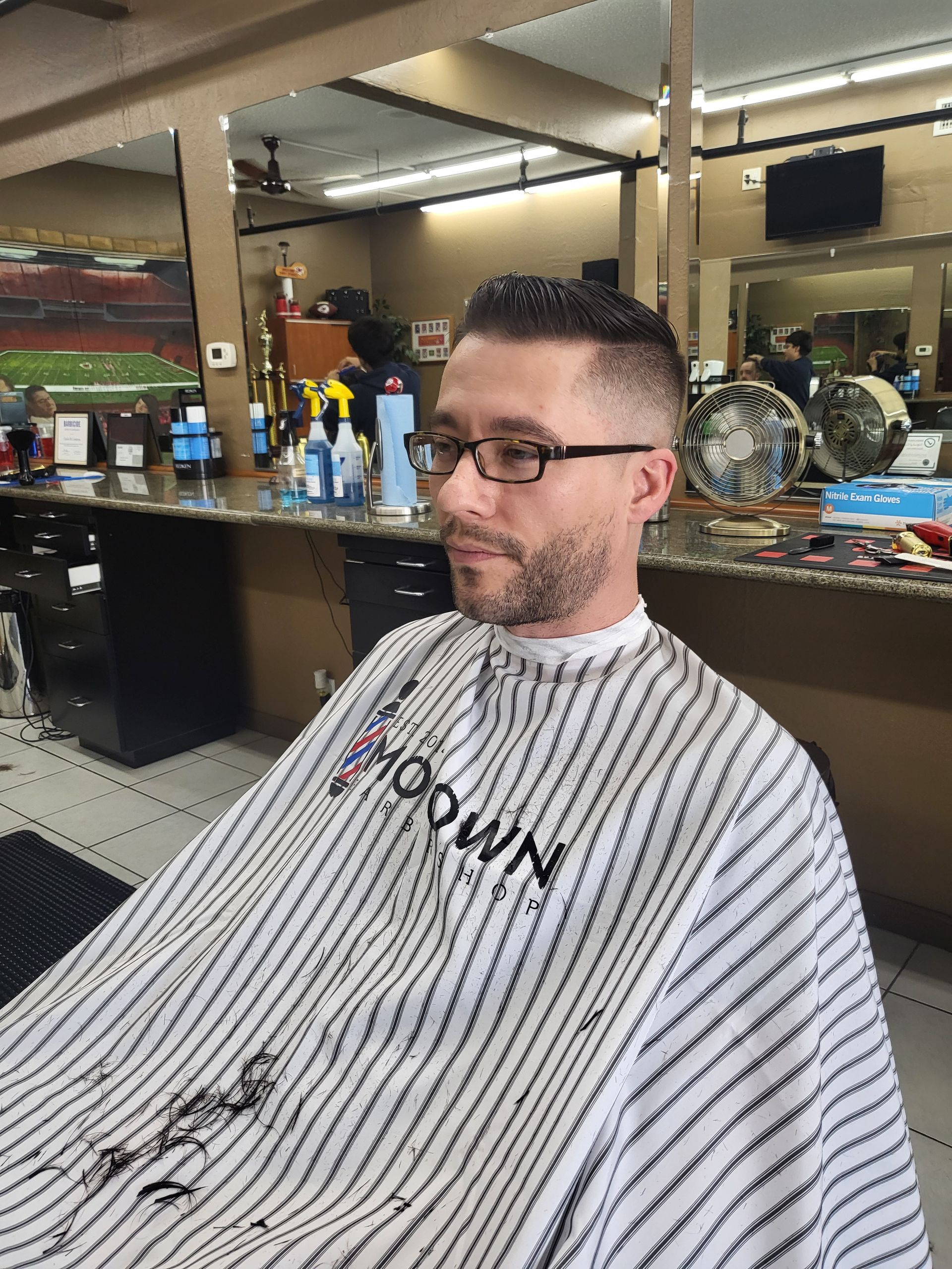 A man is getting his hair cut at a barber shop.