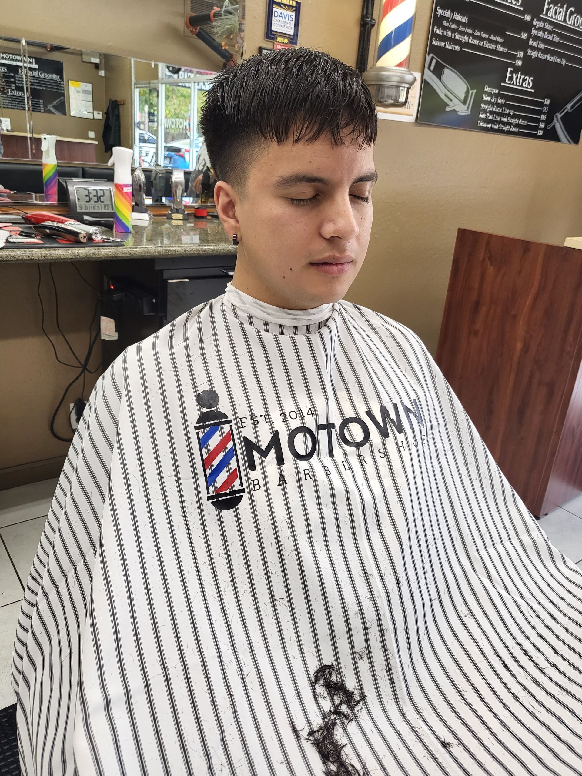 A young man is getting his hair cut at a barber shop.