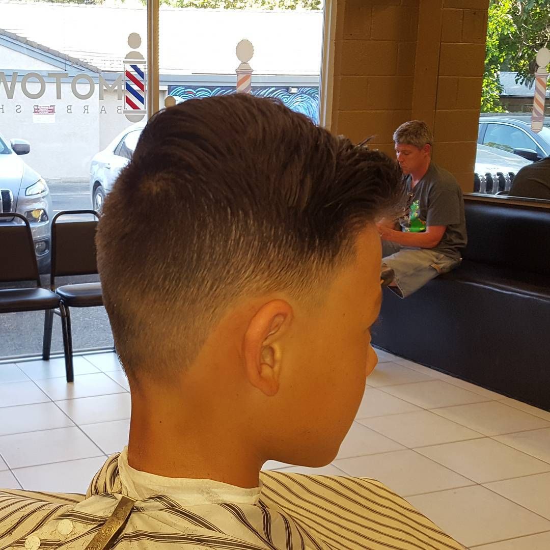 A young boy is getting his hair cut at a barber shop