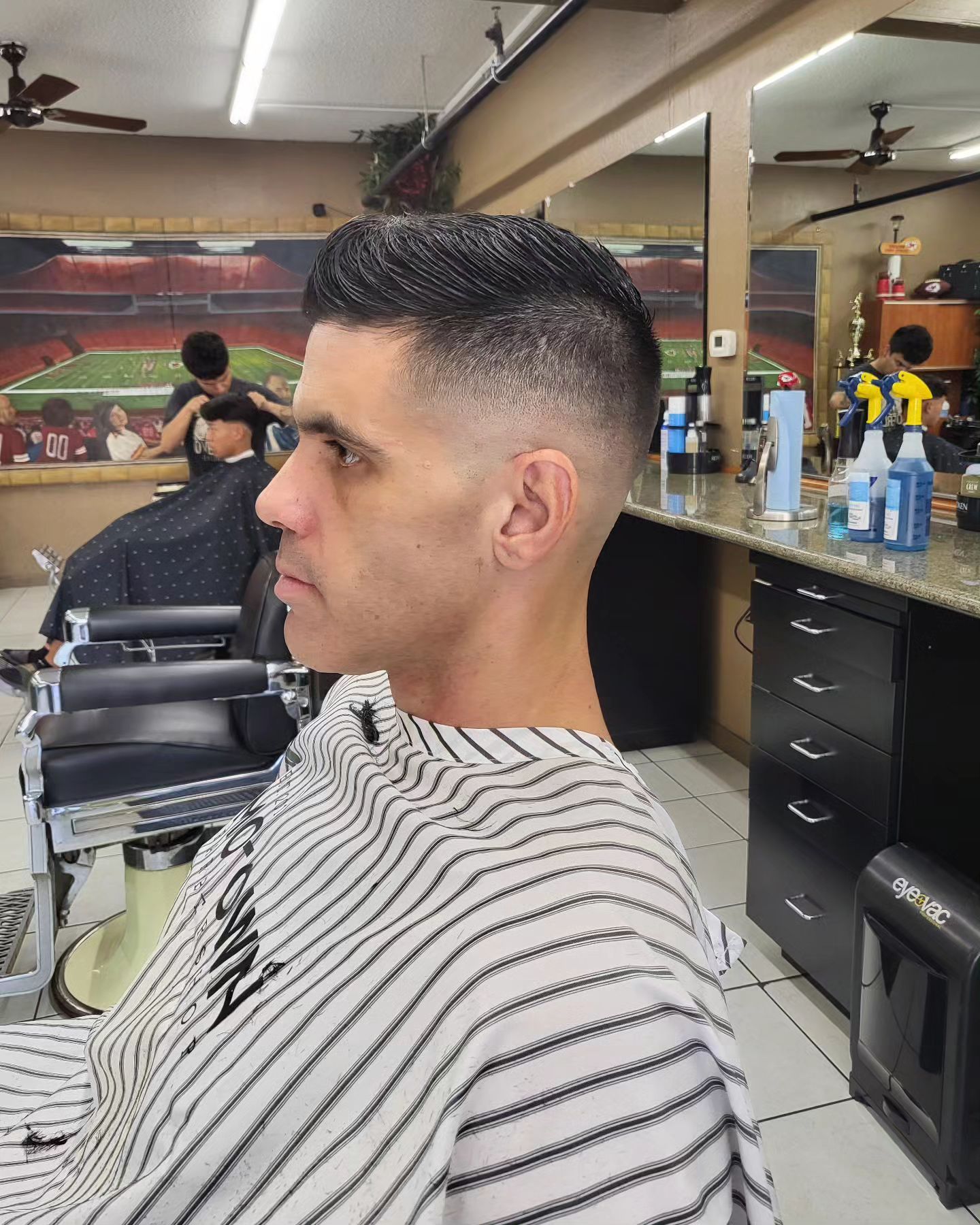 A man is getting his hair cut at a barber shop.