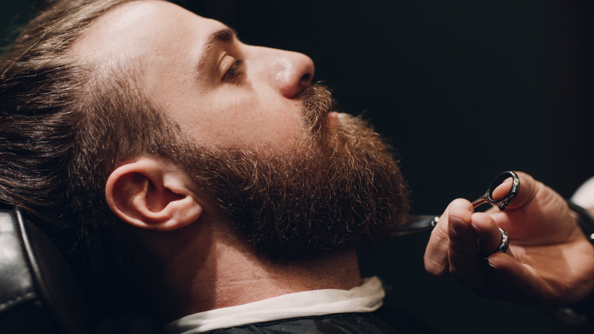 A man is getting his beard shaved by a barber.