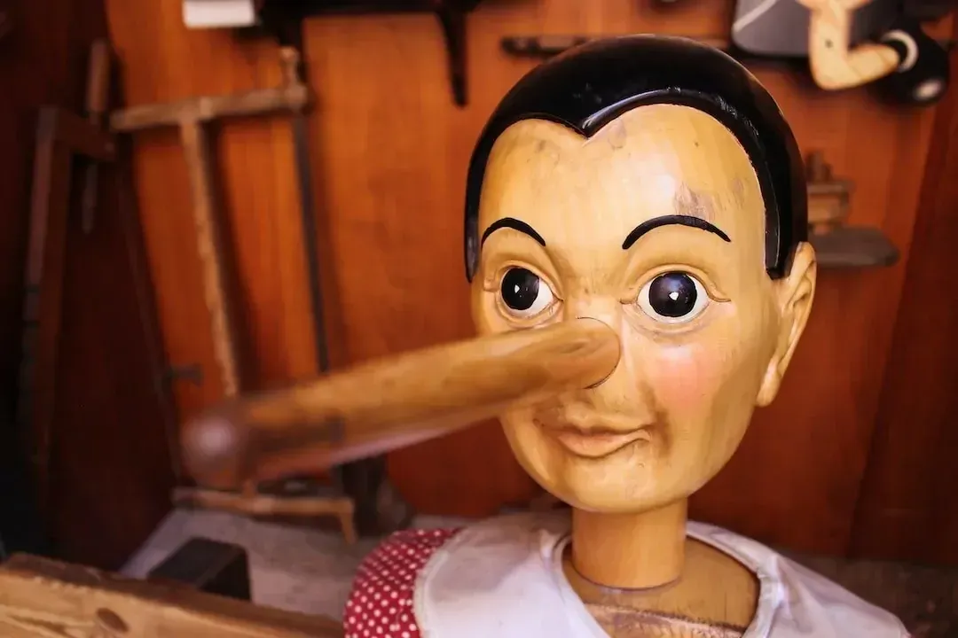 Pinocchio puppet with a long wooden nose against a blurred wooden background