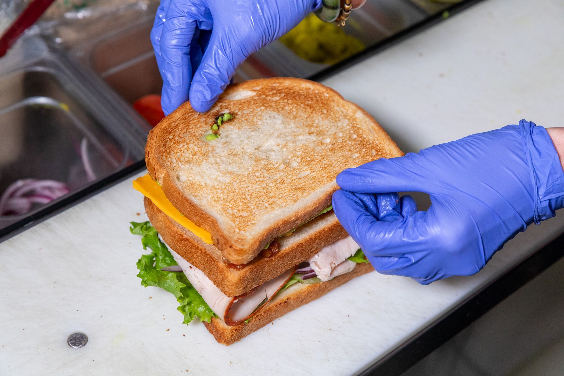 Avocado toast topped with egg, cucumber, tomatoes, and feta, being drizzled with balsamic vinaigrette.