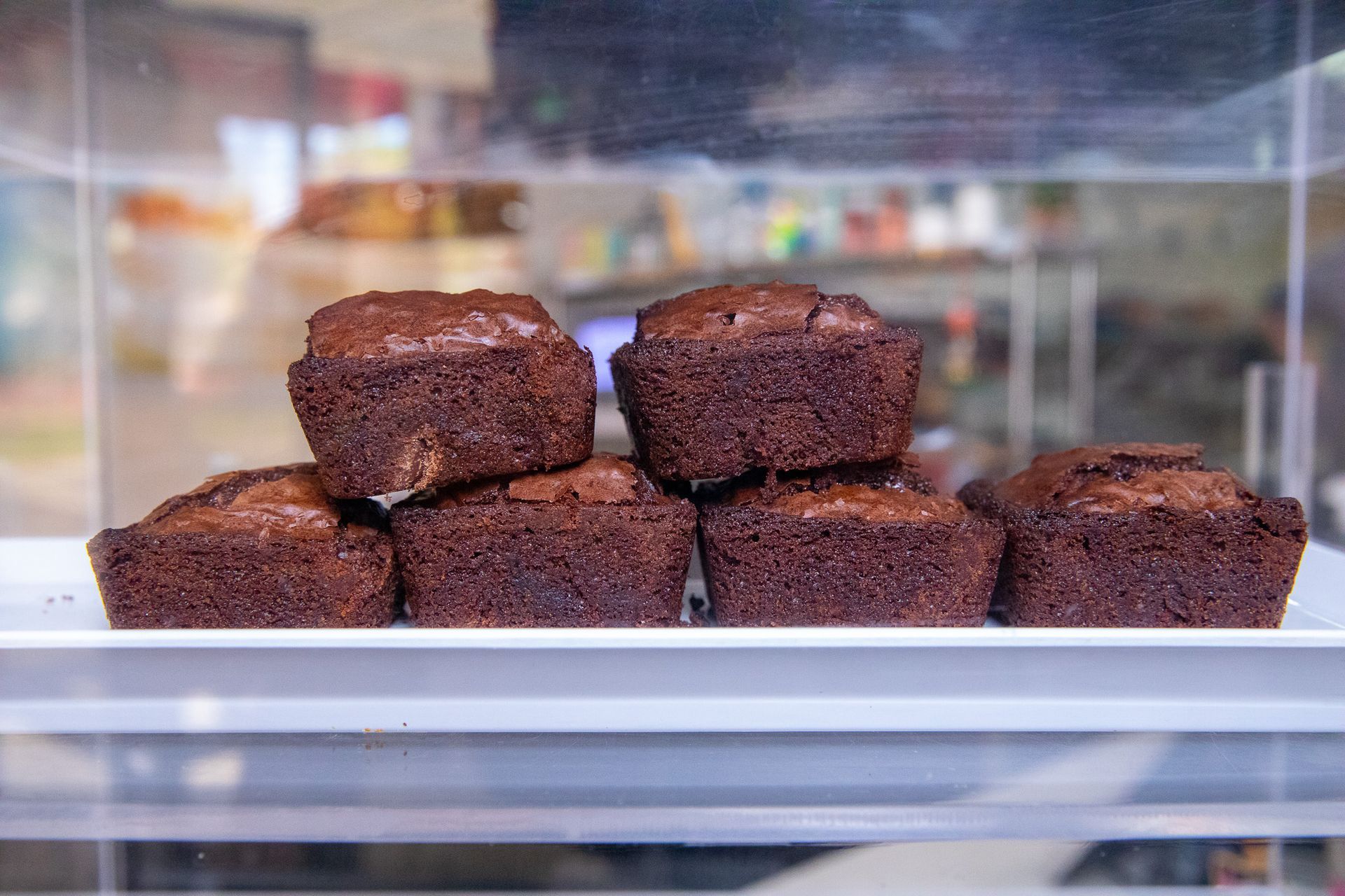 Avocado toast topped with egg, cucumber, tomatoes, and feta, being drizzled with balsamic vinaigrette.