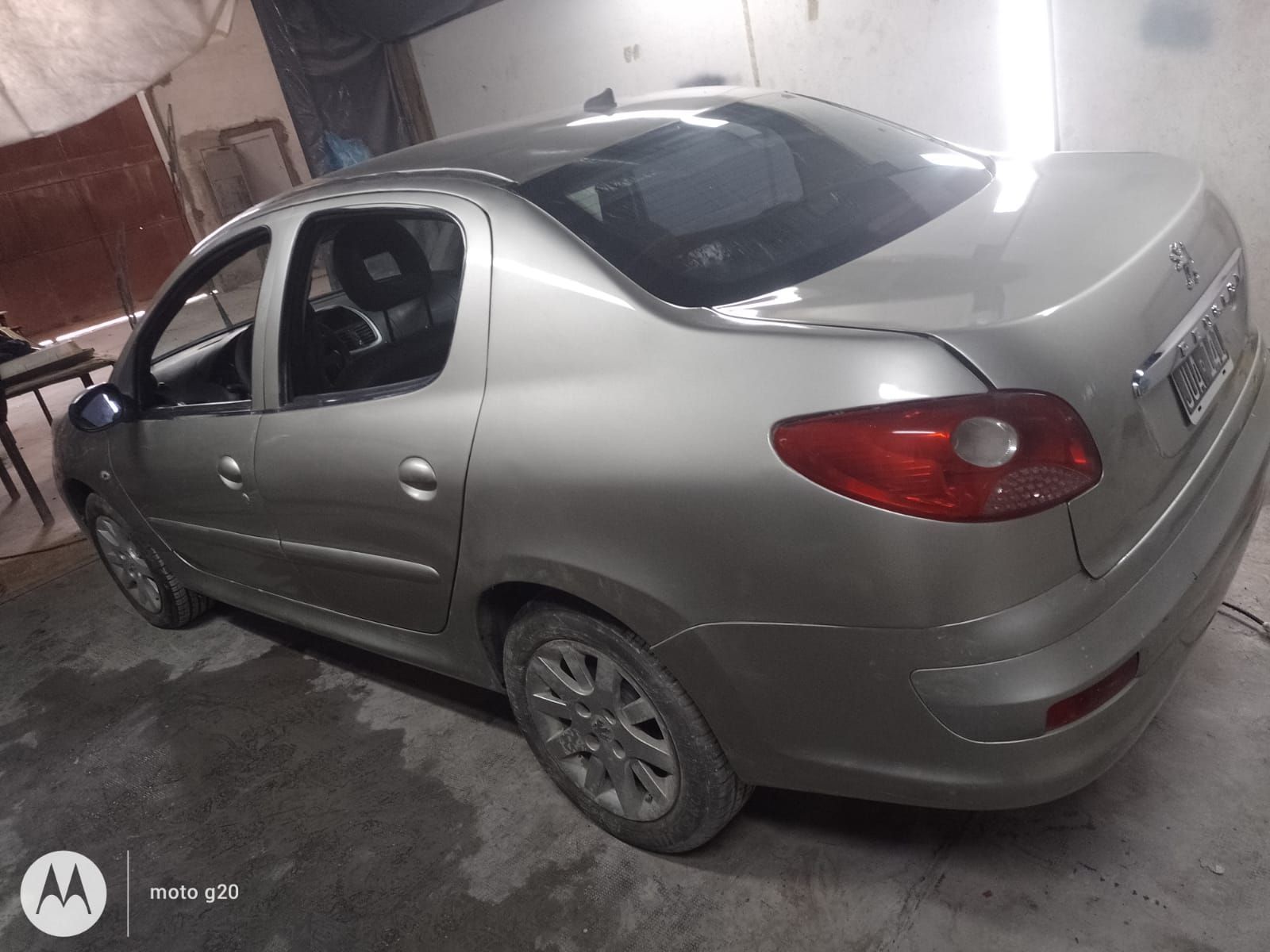 Peugeot sedán gris estacionado en un garaje.