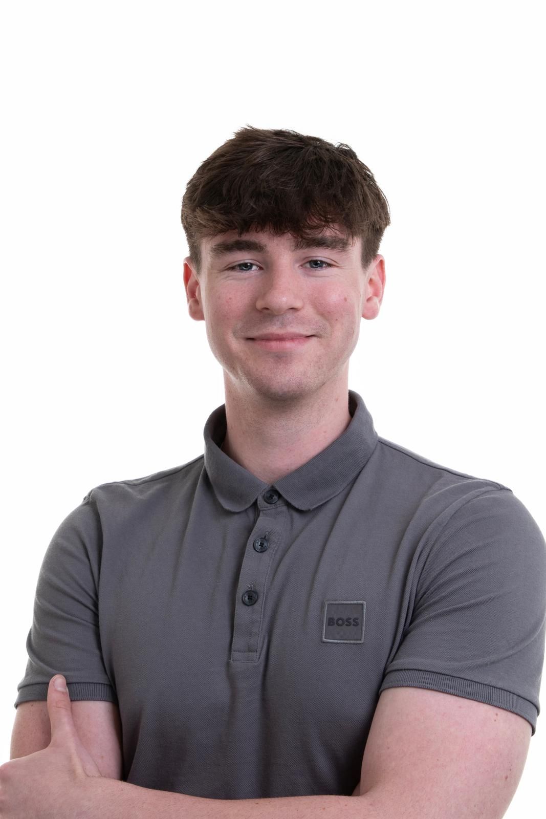 A young man wearing a grey polo shirt is smiling for the camera.