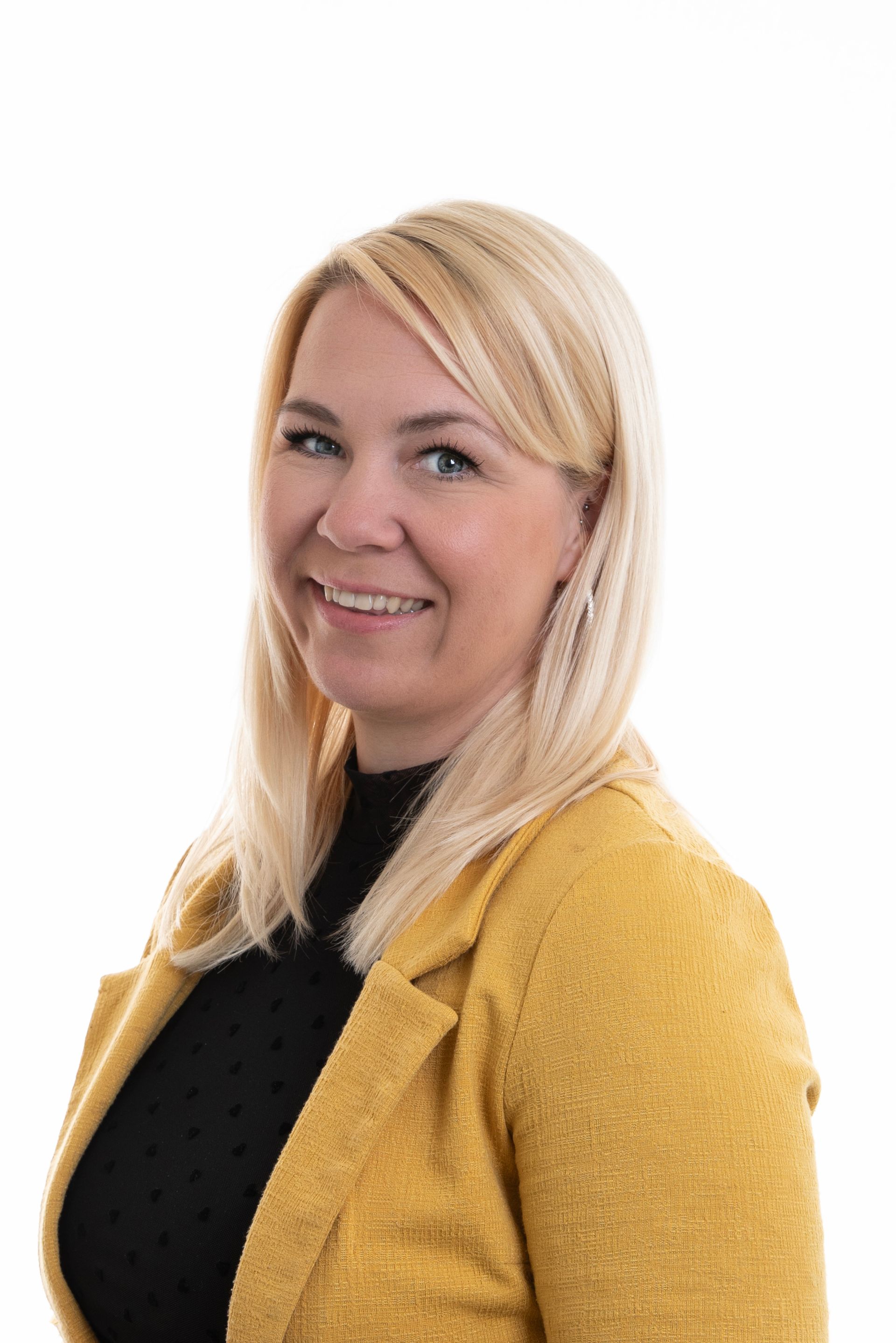 A woman wearing a yellow jacket and a black shirt is smiling.