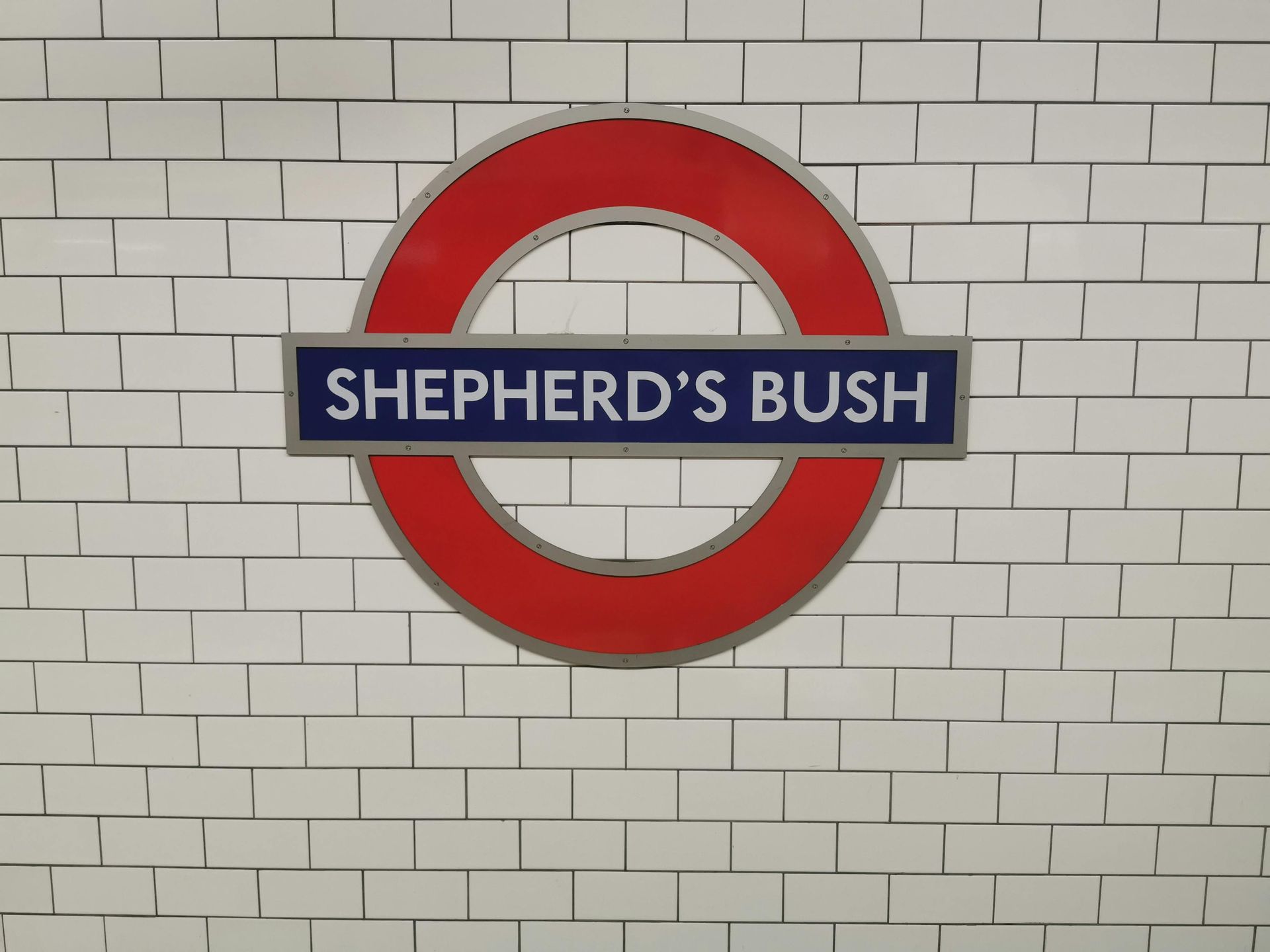 A sign for shepherd 's bush is on a white brick wall