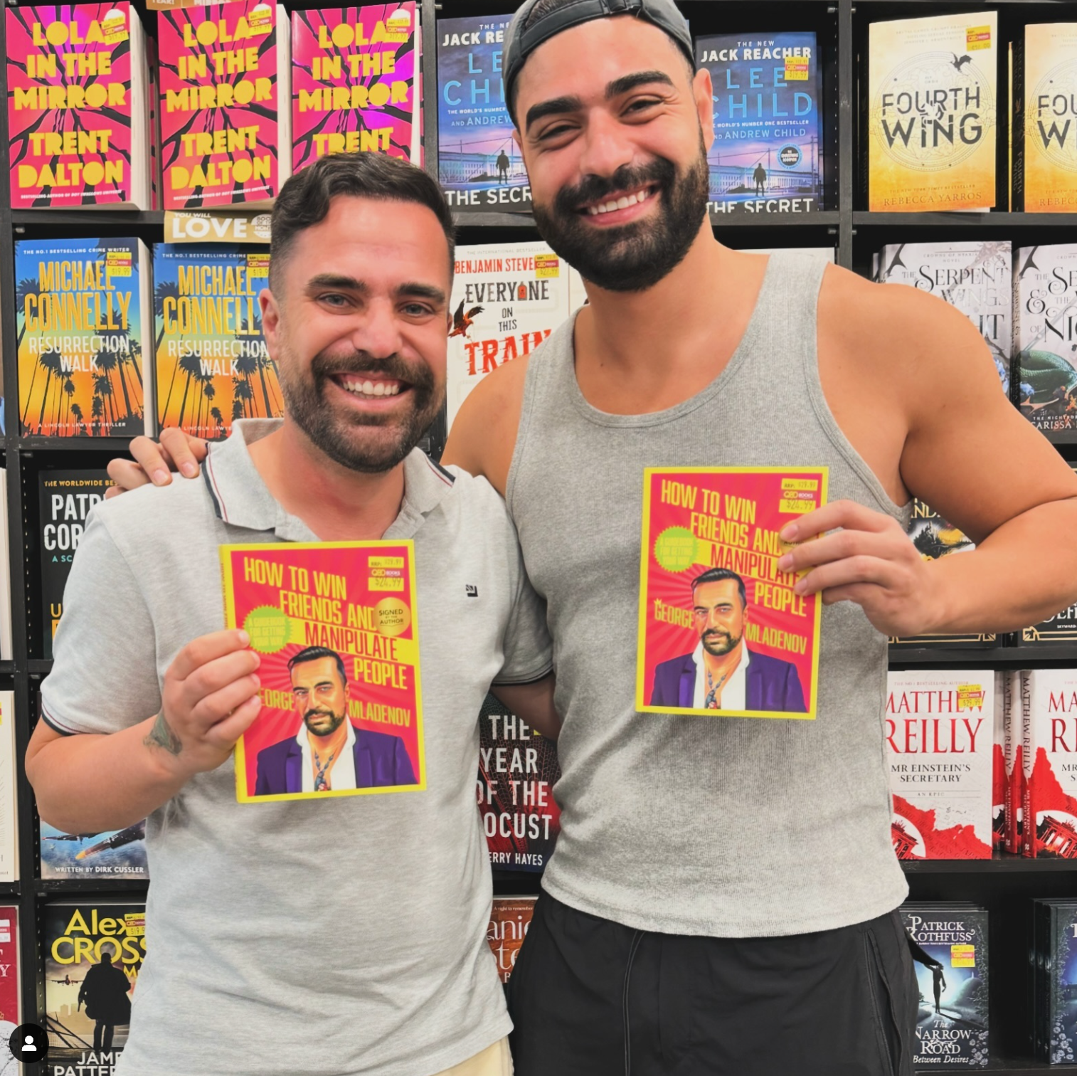 Two men standing next to each other holding a book titled how to win the heart of the people