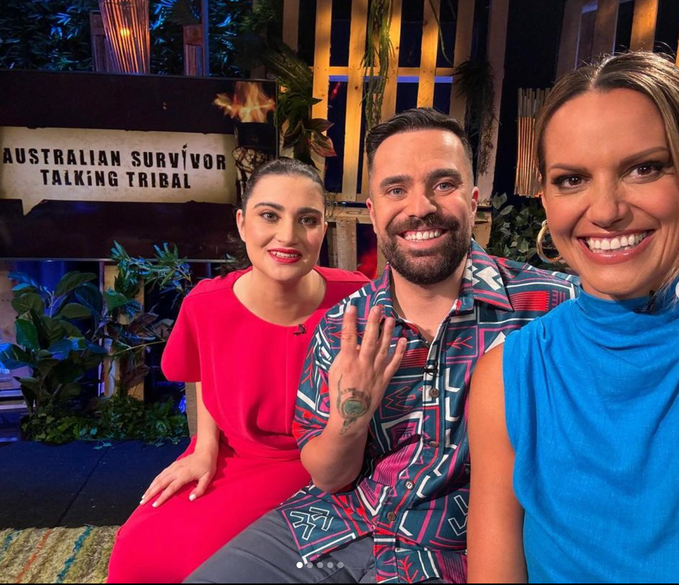 Three people are posing for a picture in front of a sign that says australian survivor talking tribal