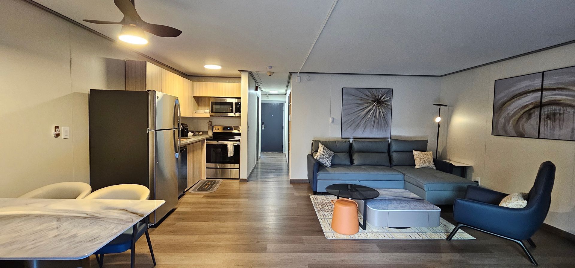 A living room with a couch , chairs , a table and a ceiling fan.