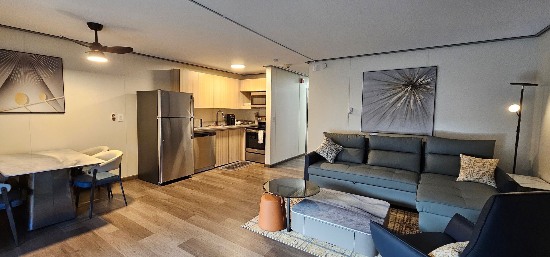 A living room with a couch , chair , table and refrigerator.