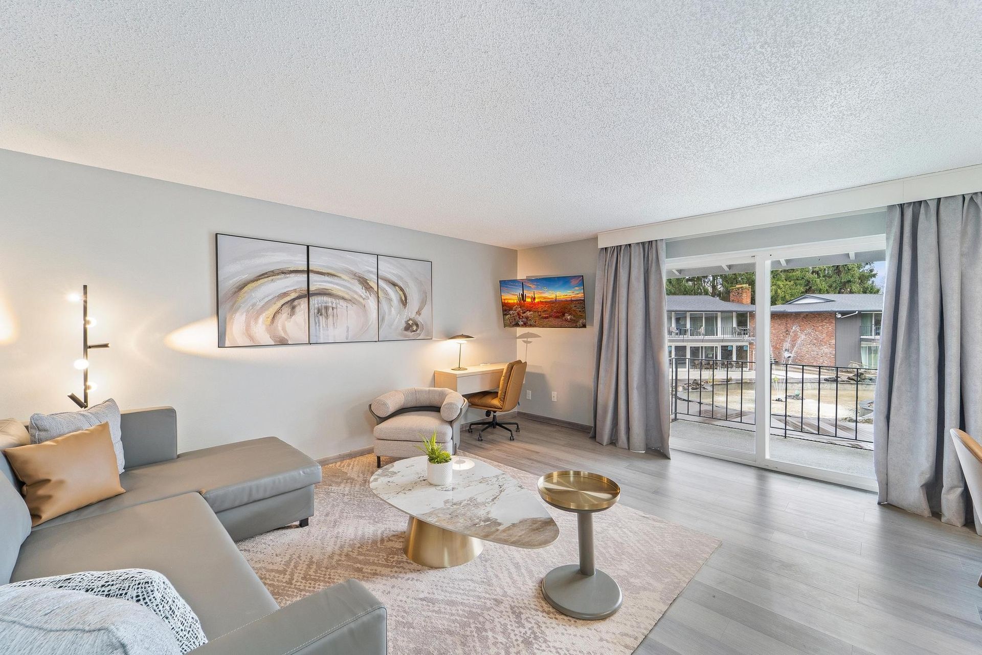 A living room with a couch , coffee table , chair and sliding glass doors leading to a balcony.