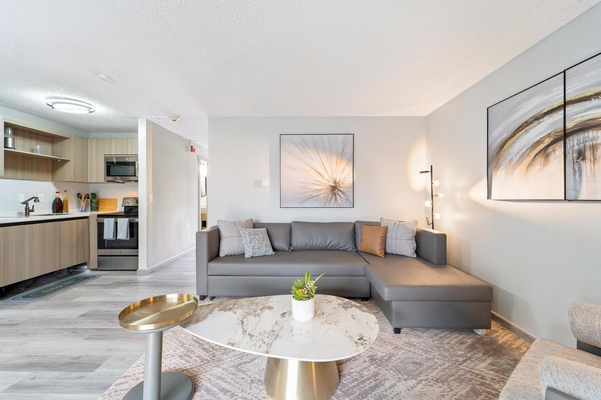 A living room with a couch , coffee table , and paintings on the wall.