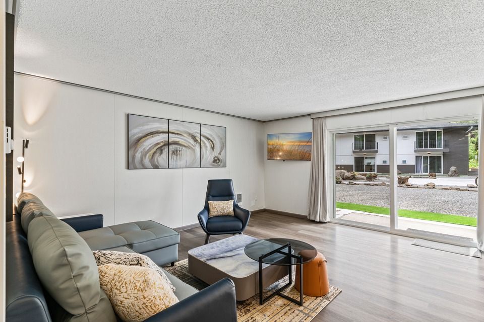 A living room with a couch , chair , coffee table and sliding glass doors.
