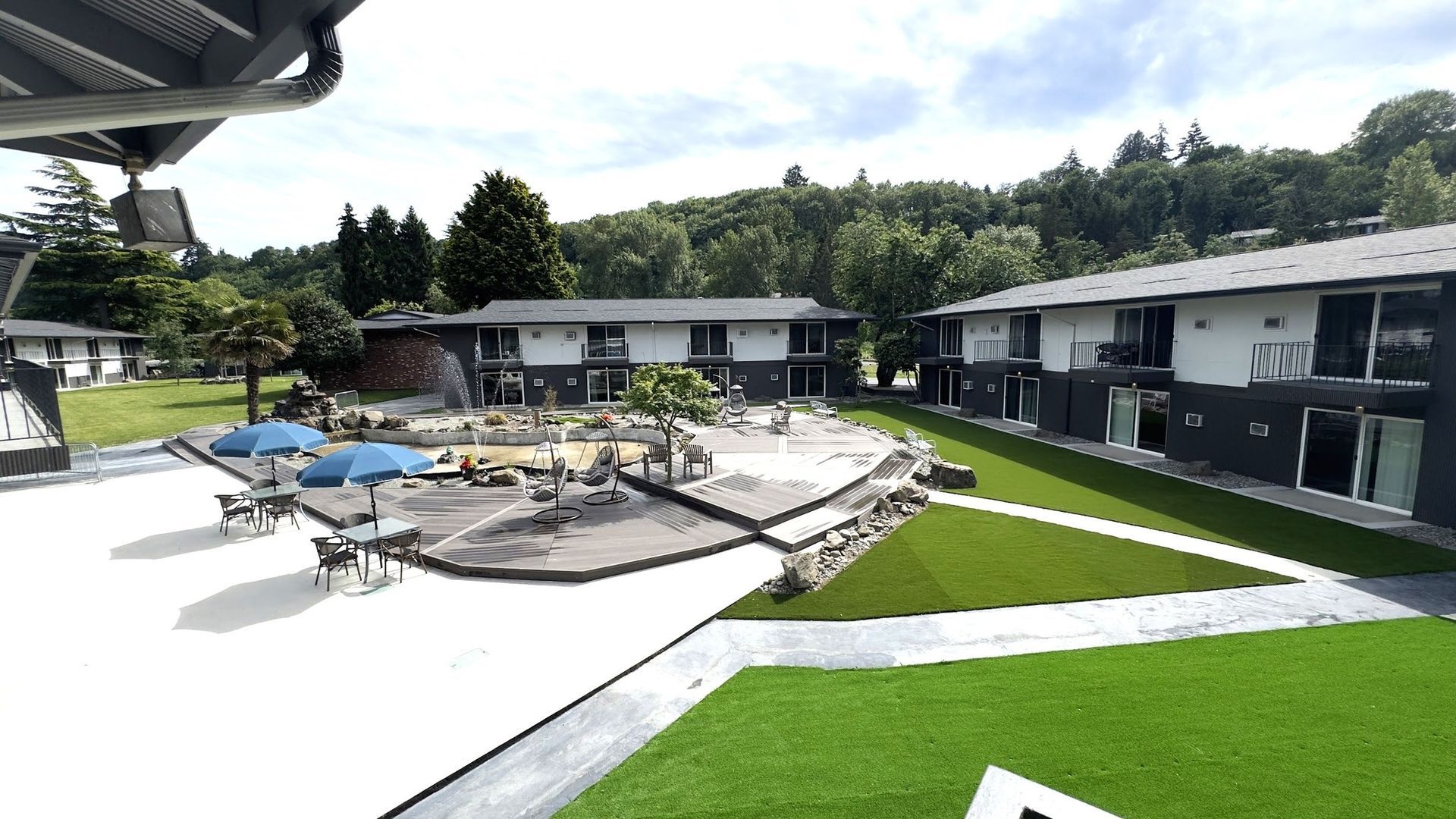 A large lawn in front of a building with umbrellas and chairs