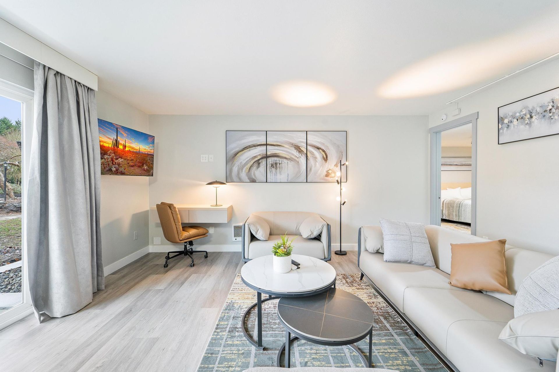 A living room with a couch , chair , coffee table and desk.