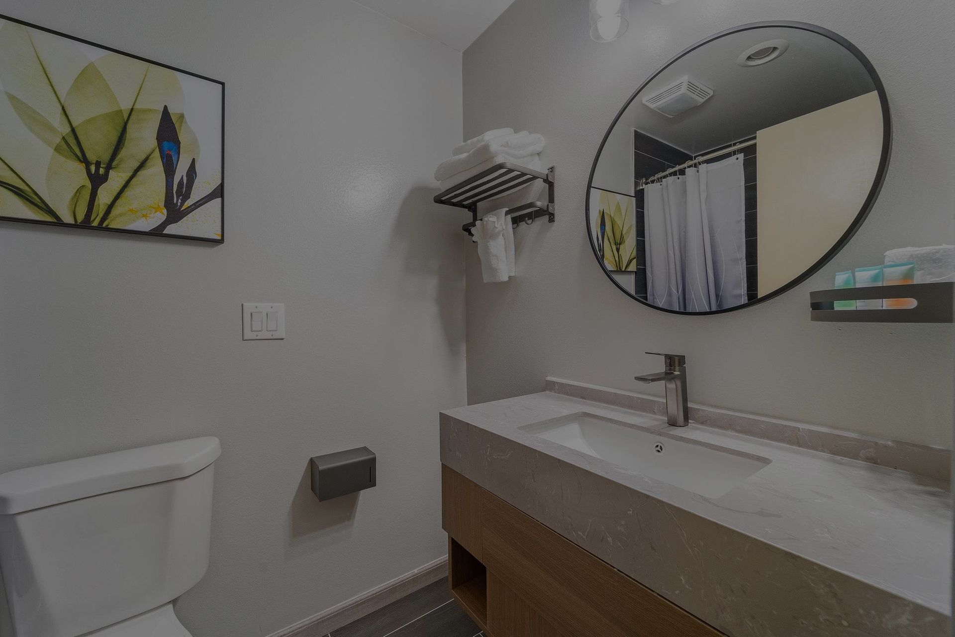 A bathroom with a toilet , sink and mirror.