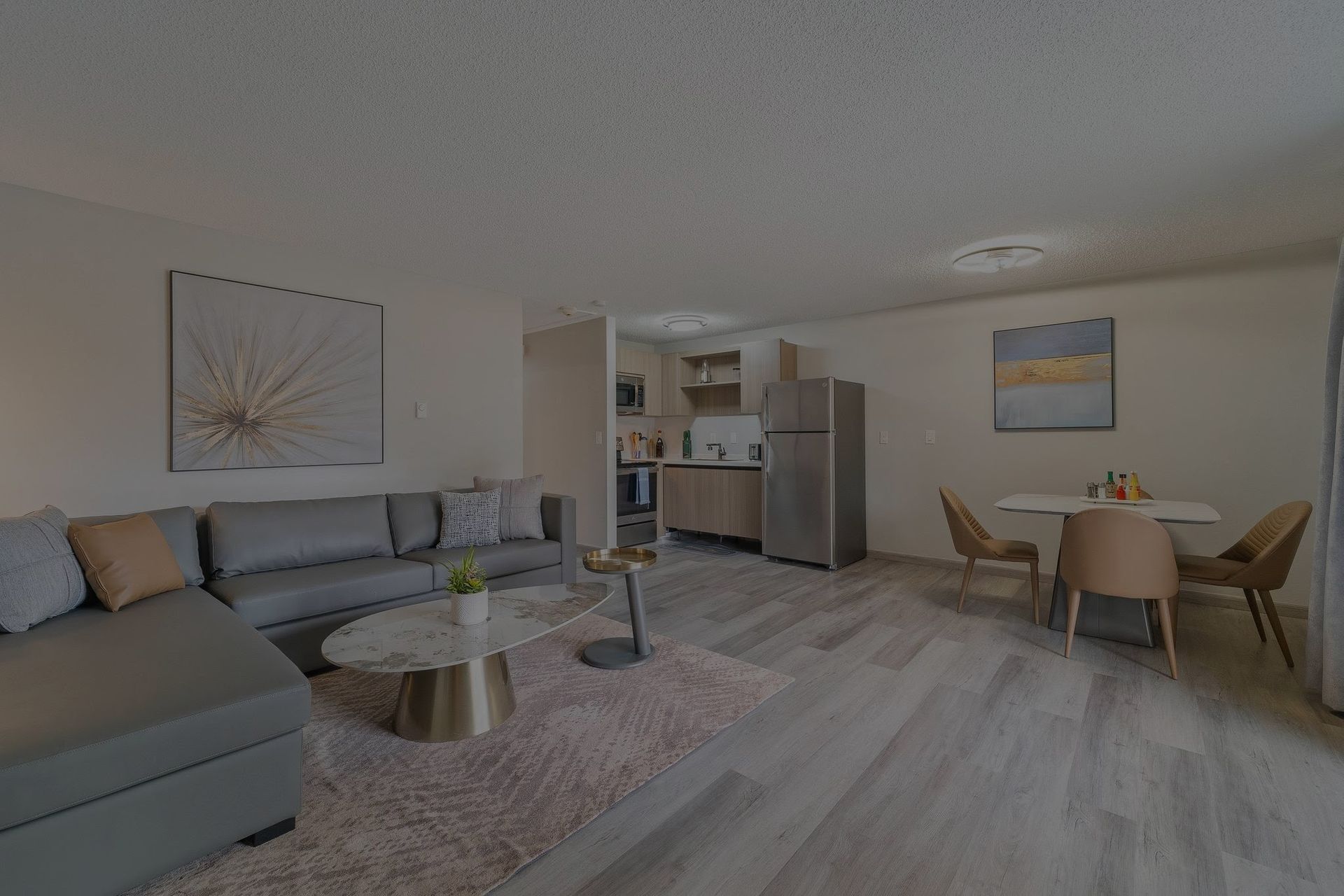 A living room with a couch , table , chairs and a refrigerator.