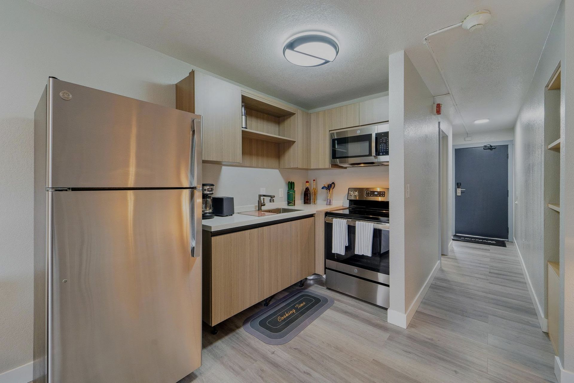 A kitchen with a refrigerator , stove , microwave and sink.