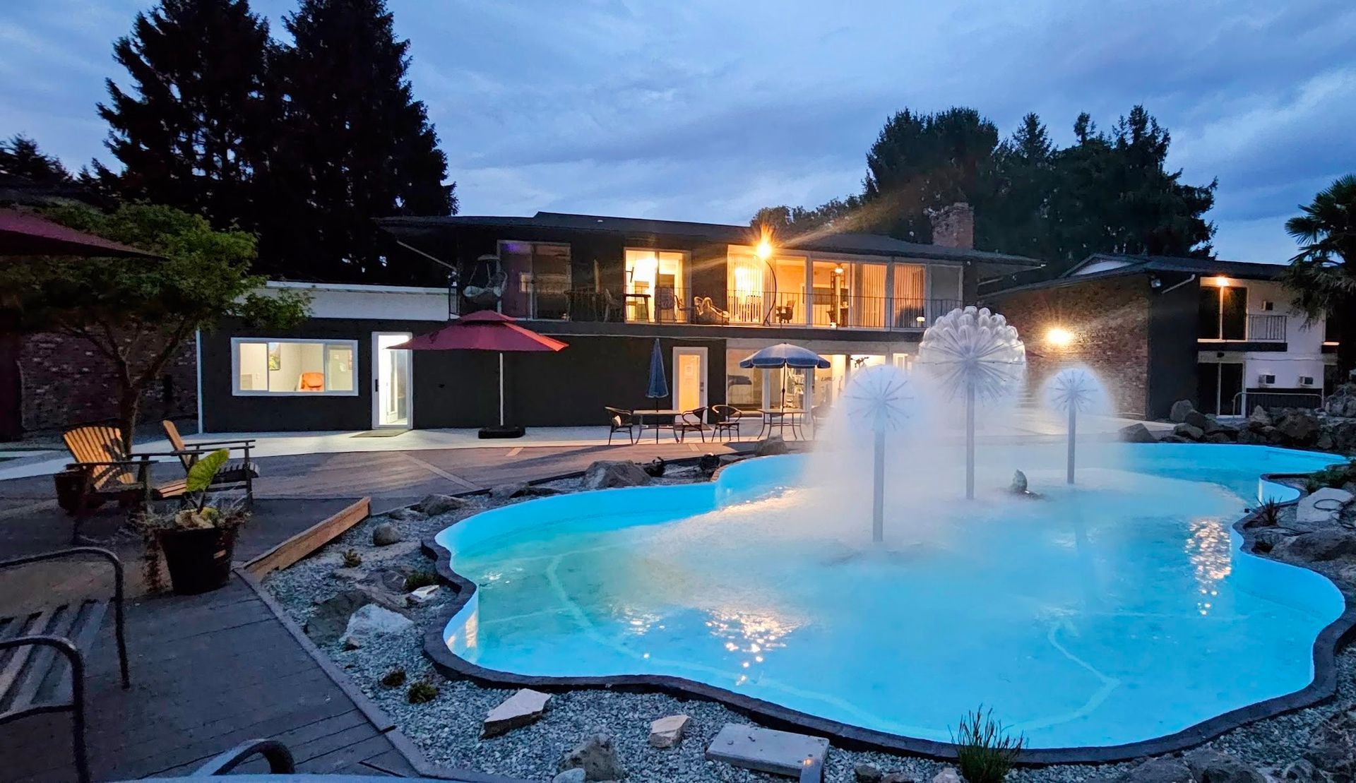 A large swimming pool with a fountain in front of a house