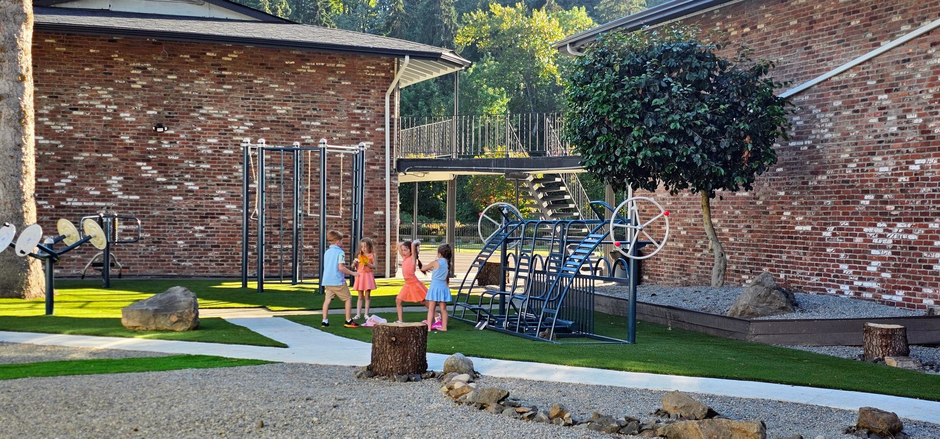 A group of children are playing in a playground in front of a brick building.
