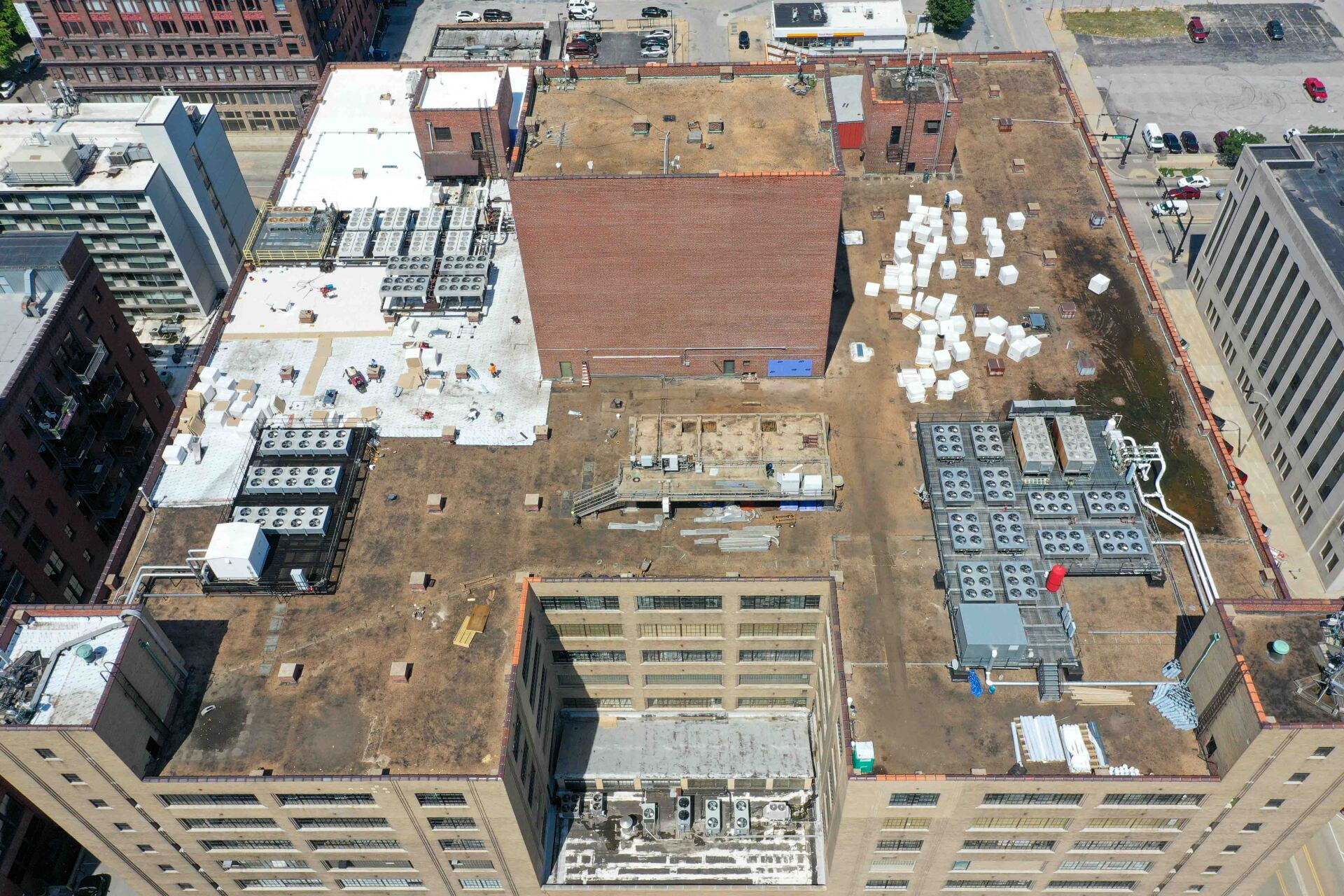 Overhead view of a city rooftop with equipment, construction, and a brick structure.