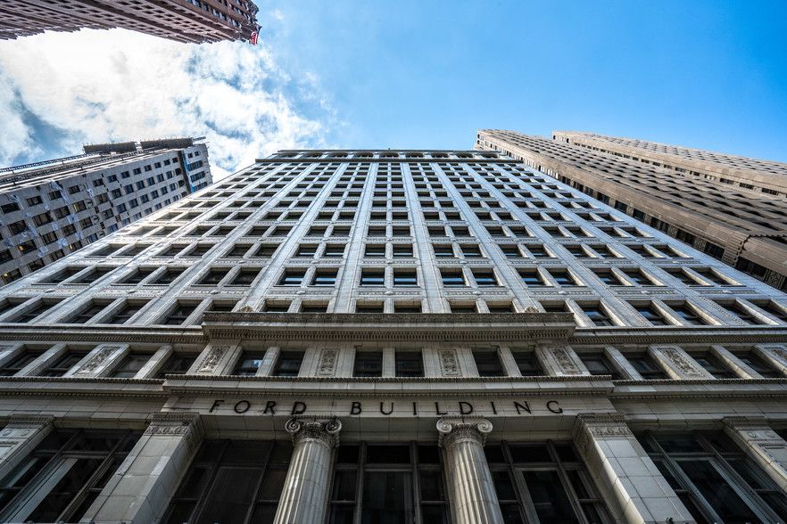 Ford Building, tall white skyscraper with columns on bottom against blue sky.