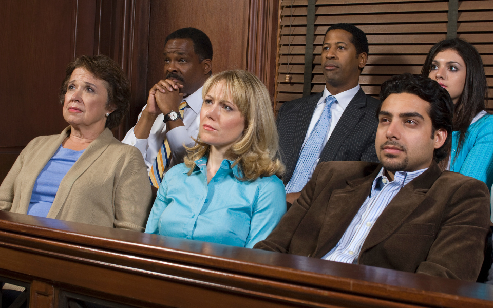 Grand Jury seated in a courtroom, listening attentively. Some display concerned expressions.