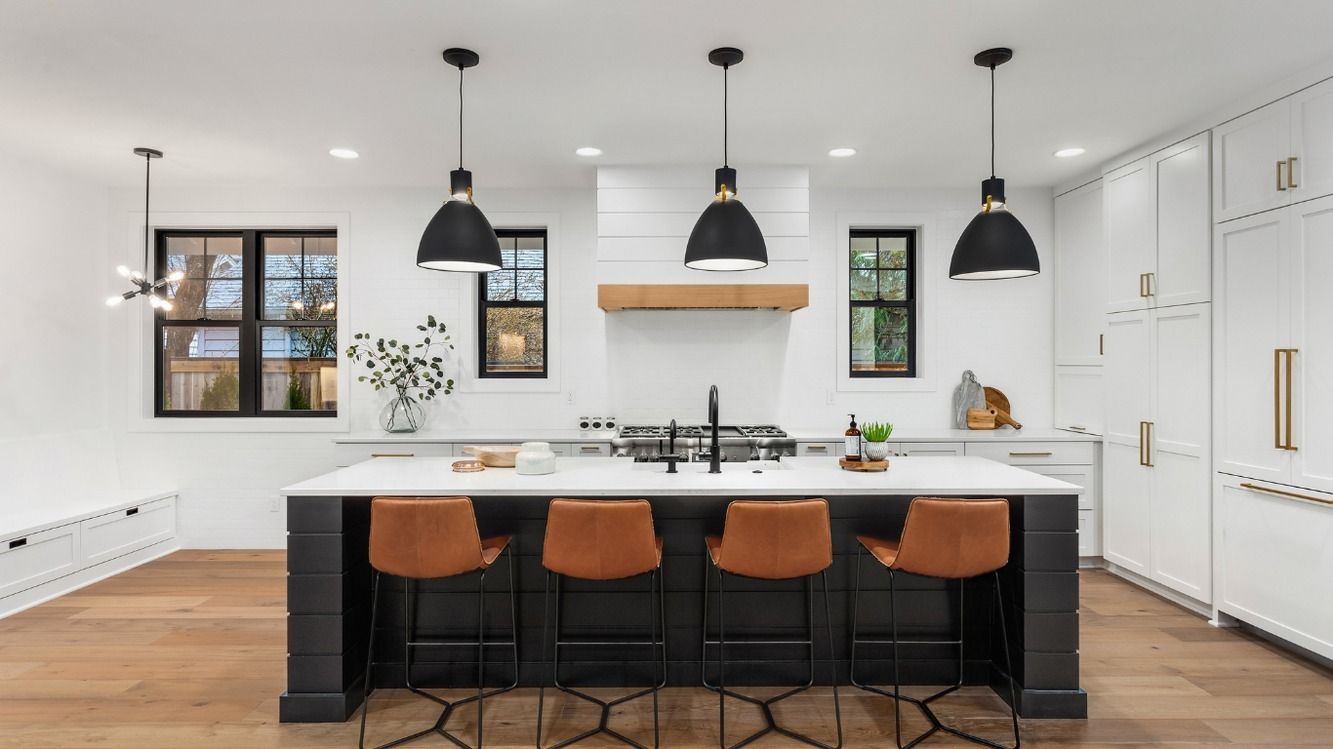 A kitchen with a large island , stools , and a stove.