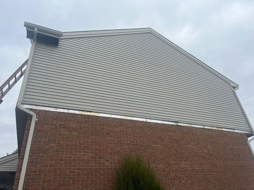 A brick building with a white roof and a tree in front of it.